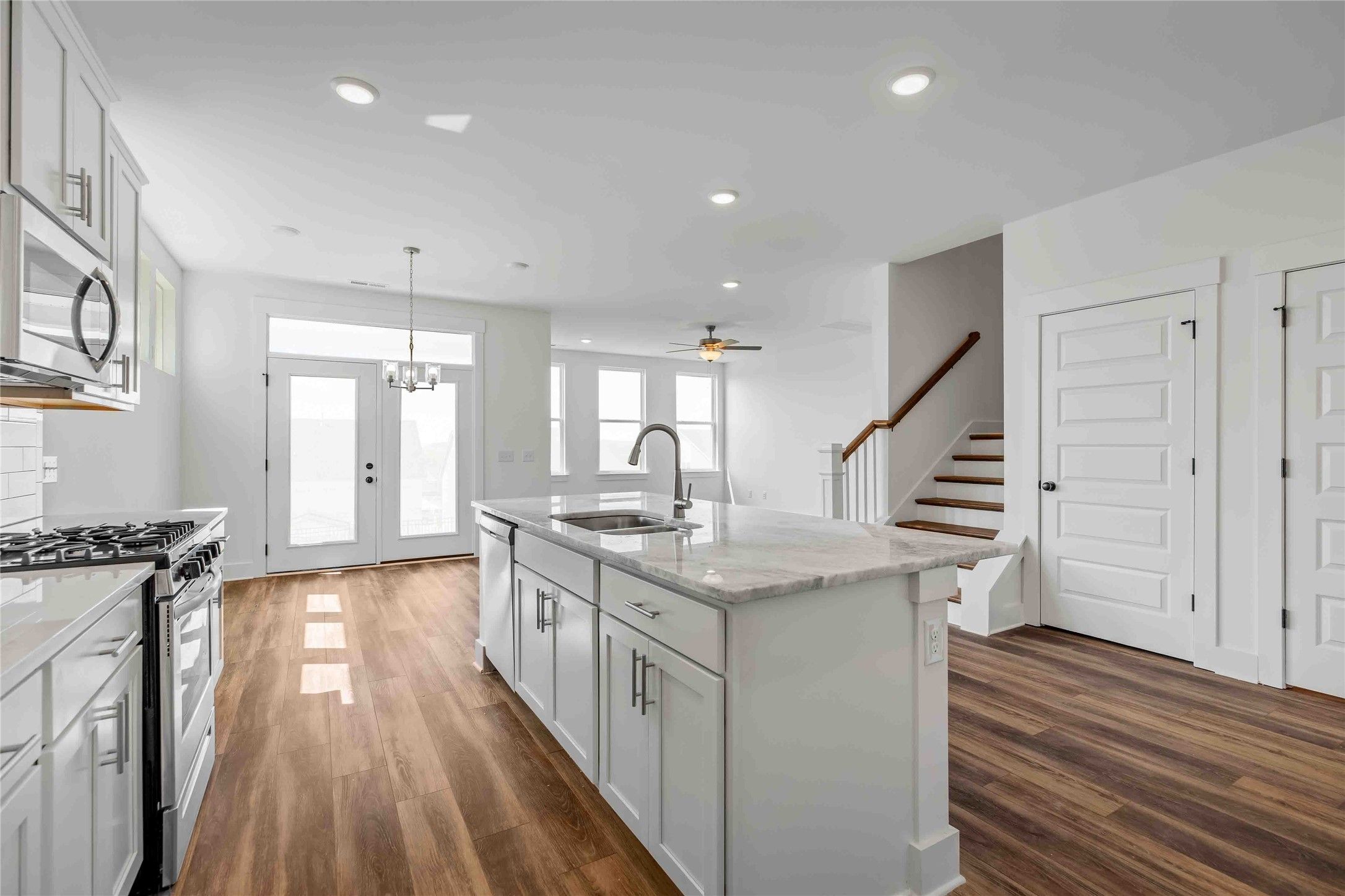 Modern kitchen with white island and quartz countertops in The Ash O floor plan by Davidson Homes in Heartland, Texas.
