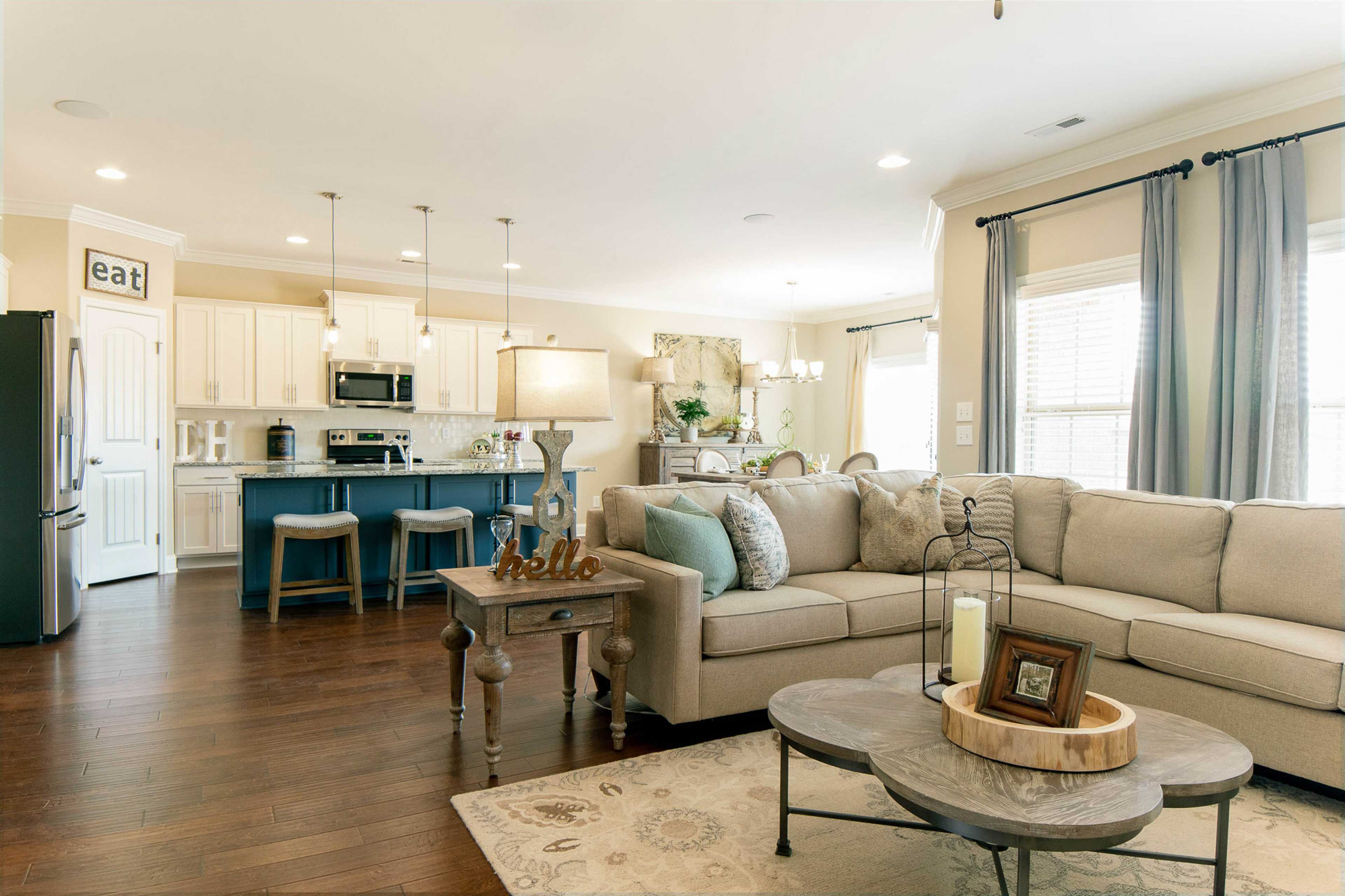 Open-concept kitchen and living room at The Dairy at Oak Grove in South Huntsville AL with hardwood floors, beige sofa, and blue island