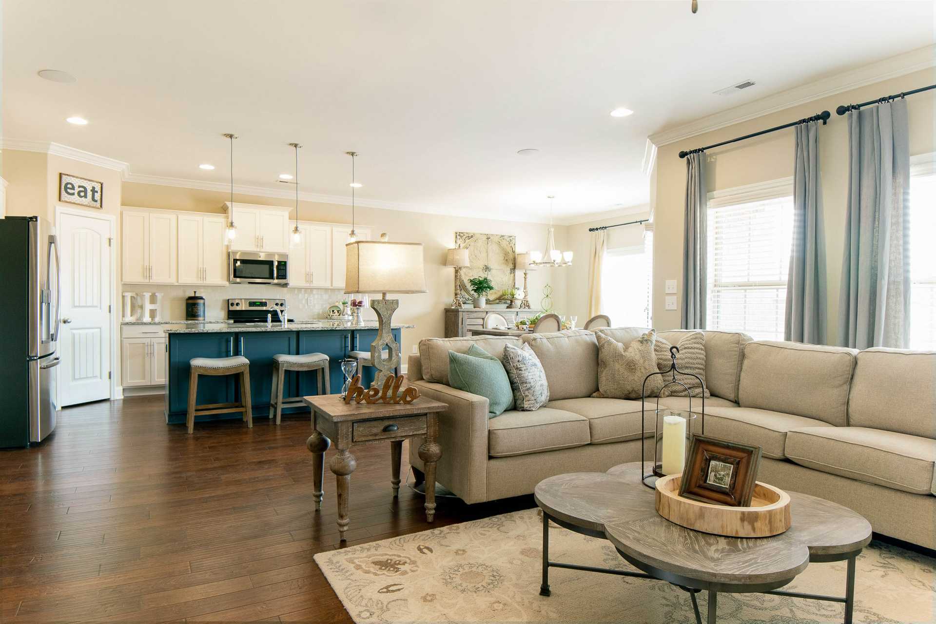Open-concept kitchen and living room at The Dairy at Oak Grove in South Huntsville AL with hardwood floors, beige sofa, and blue island