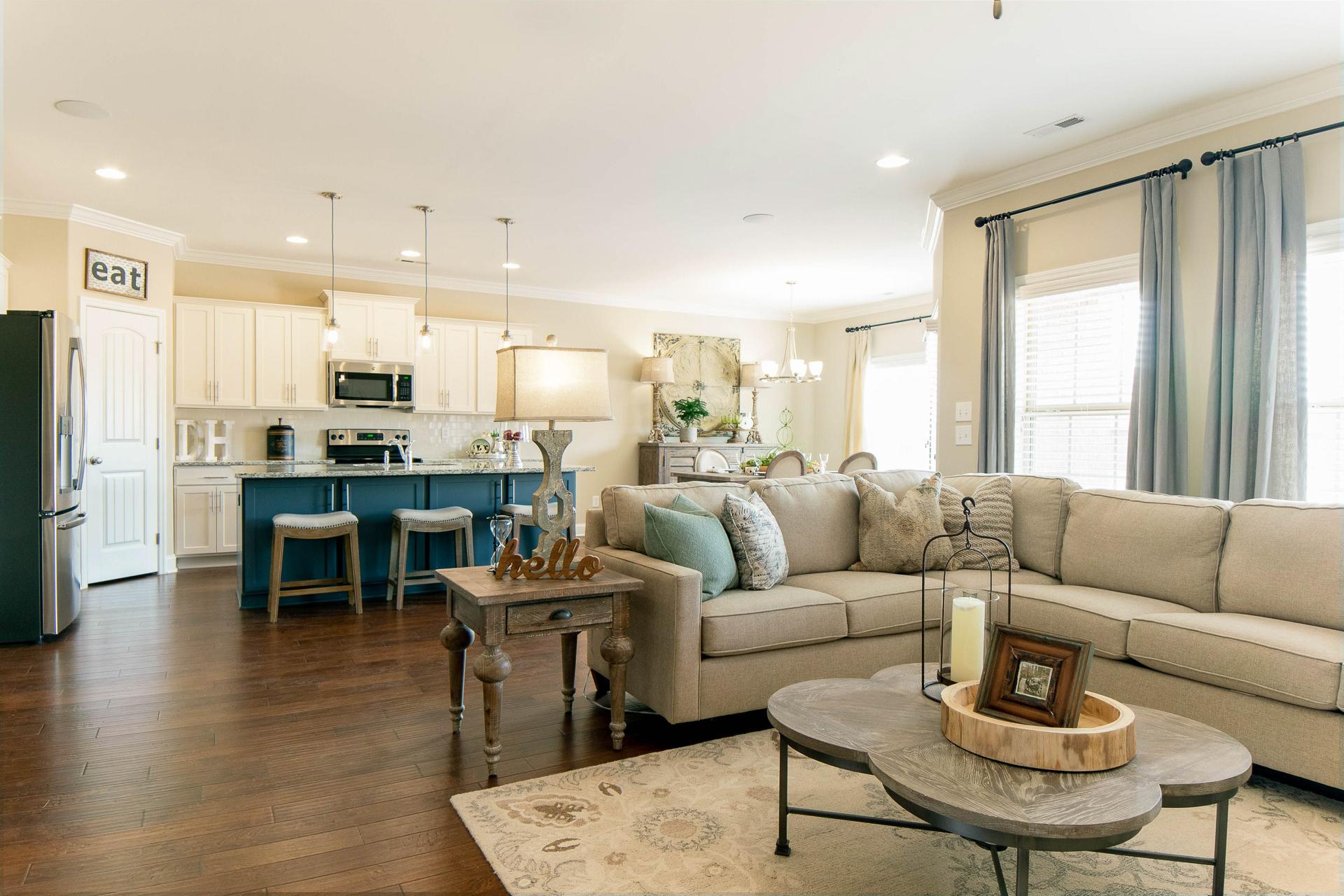 Open-concept kitchen and living room at The Dairy at Oak Grove in South Huntsville AL with hardwood floors, beige sofa, and blue island