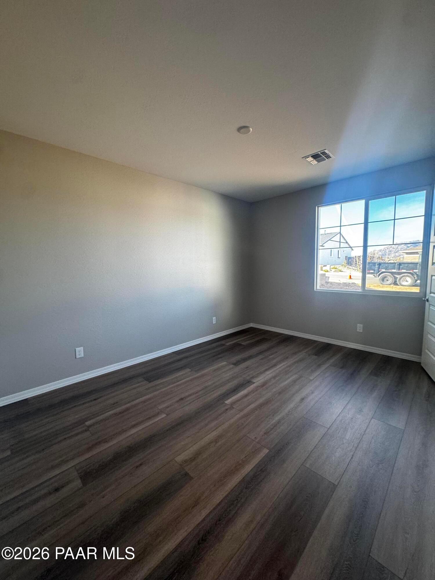 Empty bedroom with light gray walls, luxury vinyl plank floors, and large window overlooking construction in Davidson Homes Daybreak B, Prescott AZ