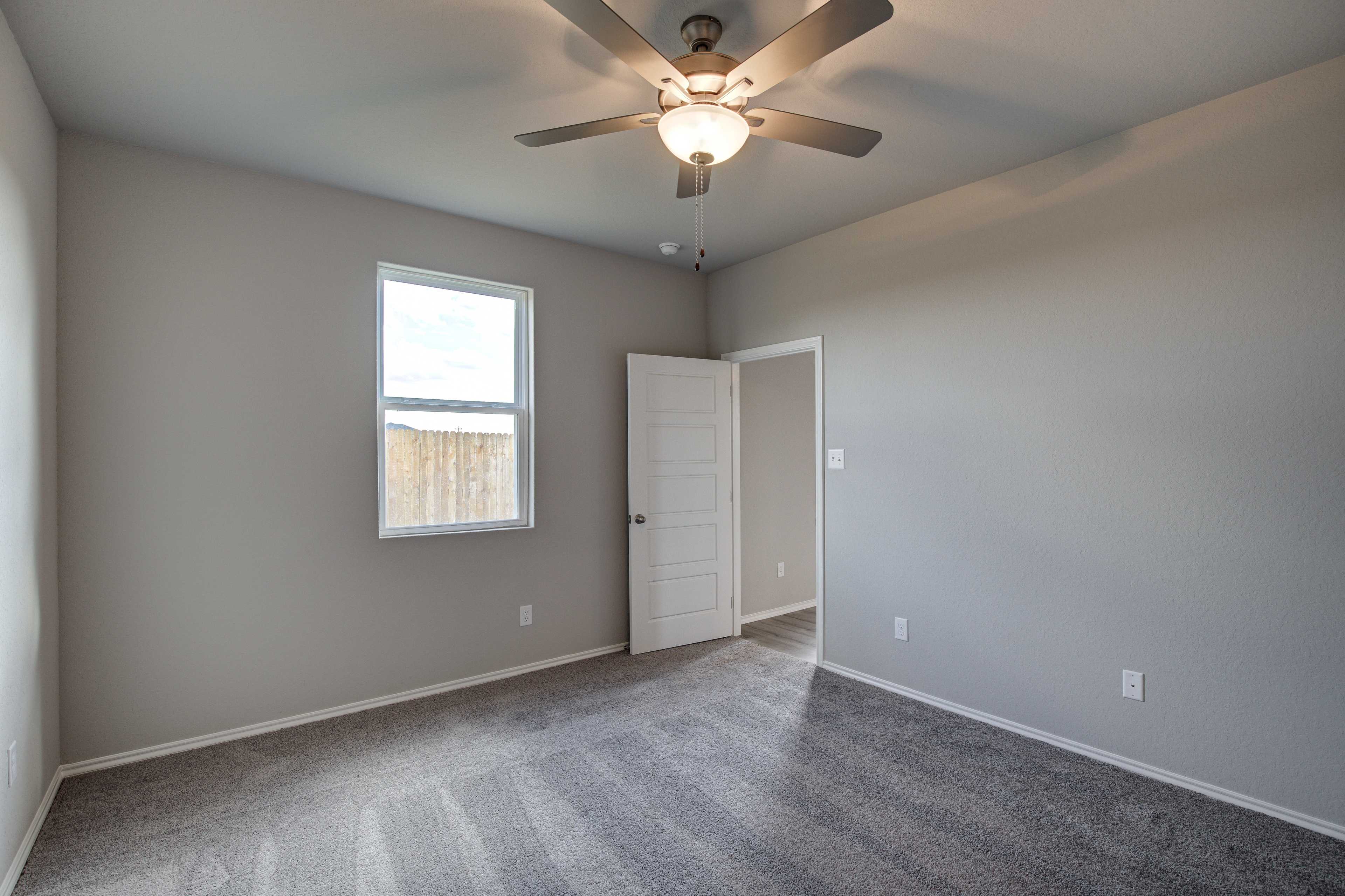 Spacious Blanco B bedroom with gray walls, lighted ceiling fan, large window, open door, and plush carpet