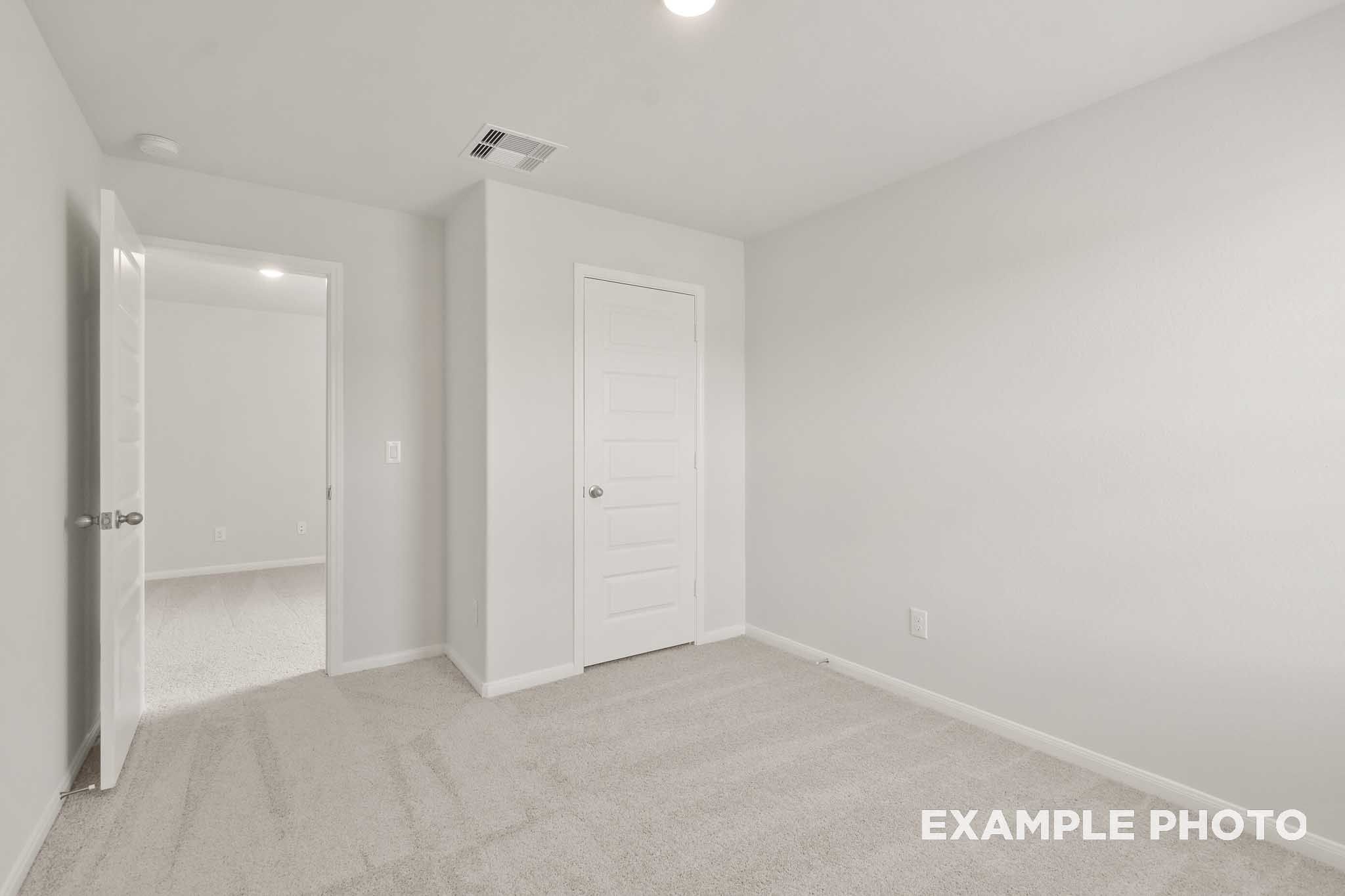 Spacious carpeted bedroom with white doors in The Brazos, a 5-bedroom Davidson Homes new construction in Beasley, Texas