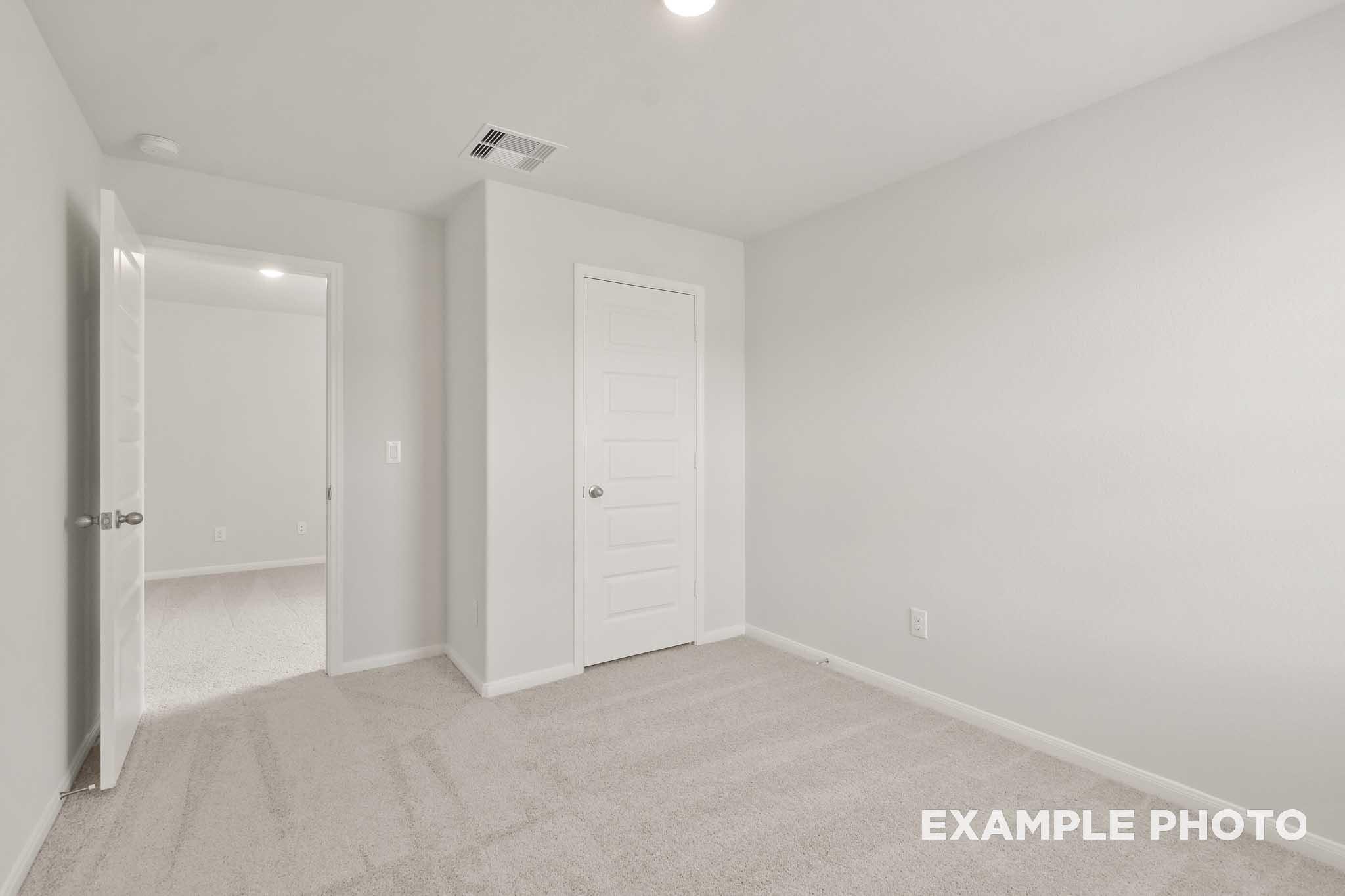 Spacious carpeted bedroom with white doors in The Brazos, a 5-bedroom Davidson Homes new construction in Beasley, Texas