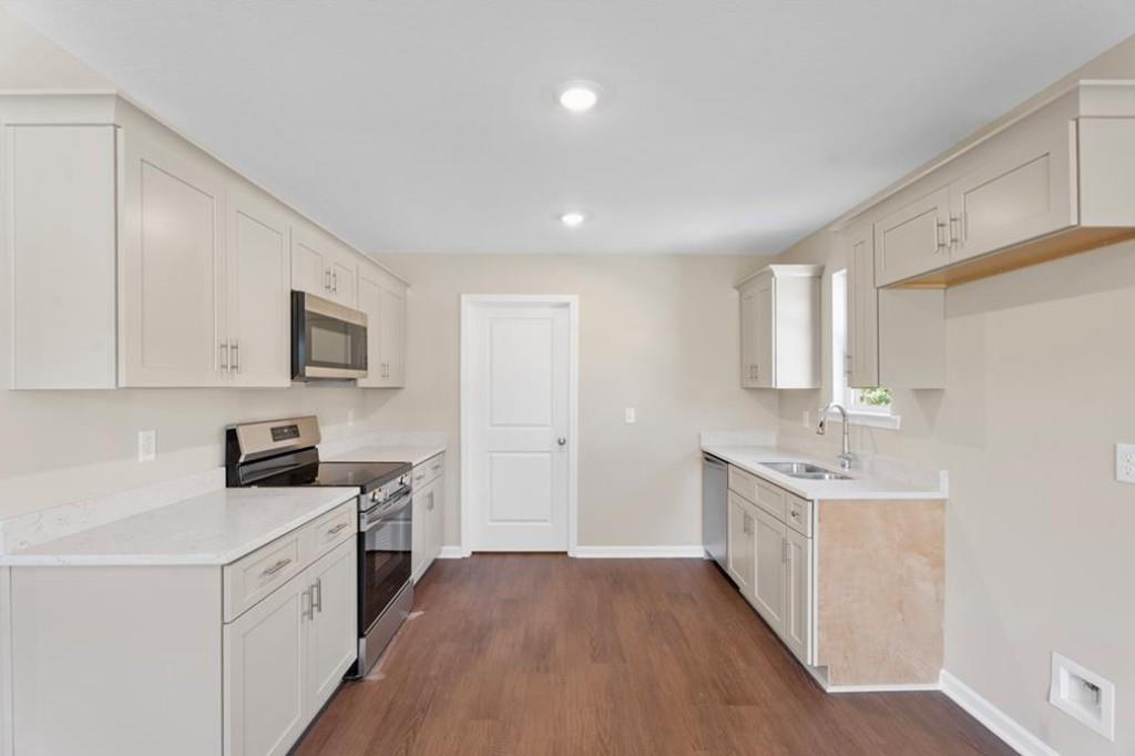 Modern white shaker kitchen with granite counters, stainless appliances, hardwood floors in Davidson Homes The Washington, Phenix City, Alabama