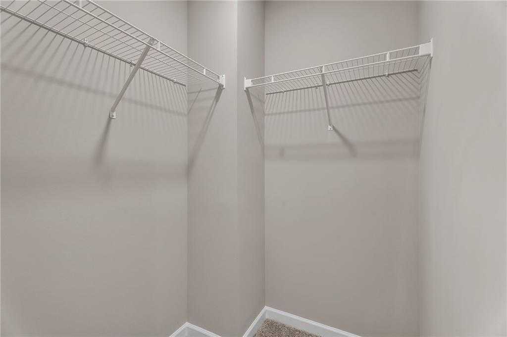 Spacious walk-in closet with white wire shelving on beige walls in Davidson Homes The Bartlett, Phenix City, Alabama