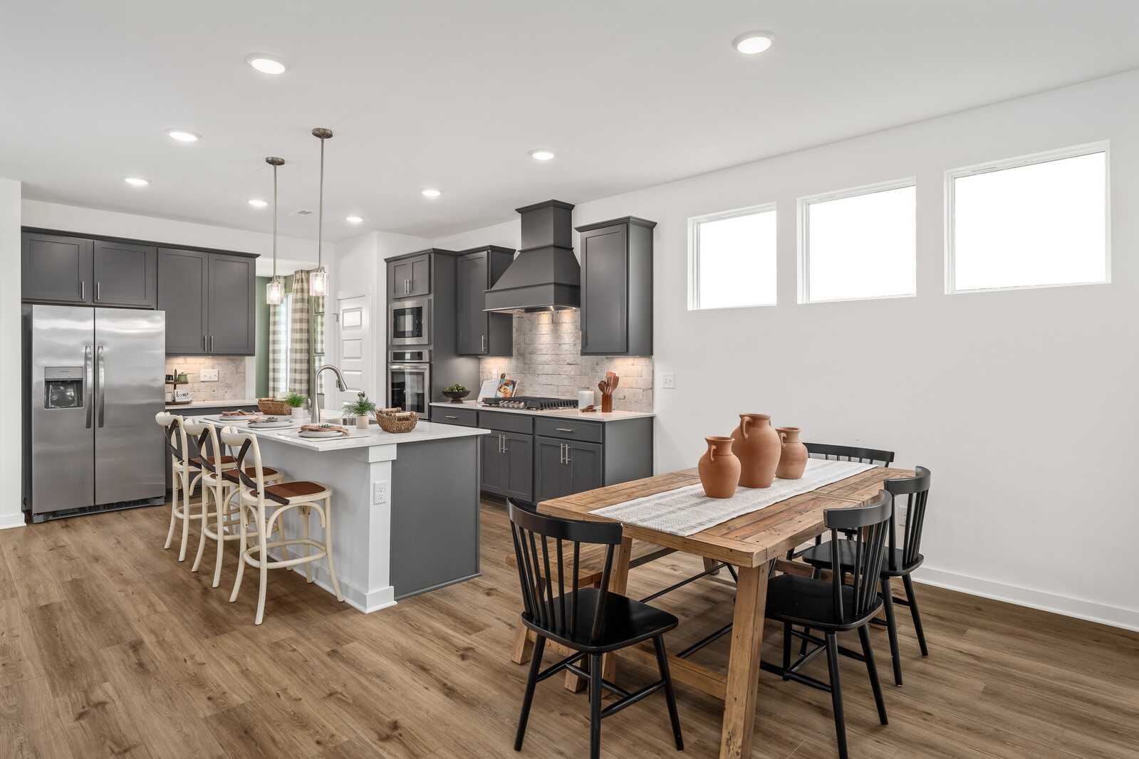 Modern open-concept kitchen at Calista Farms in White House Tennessee with gray cabinets, island bar, and hardwood floors