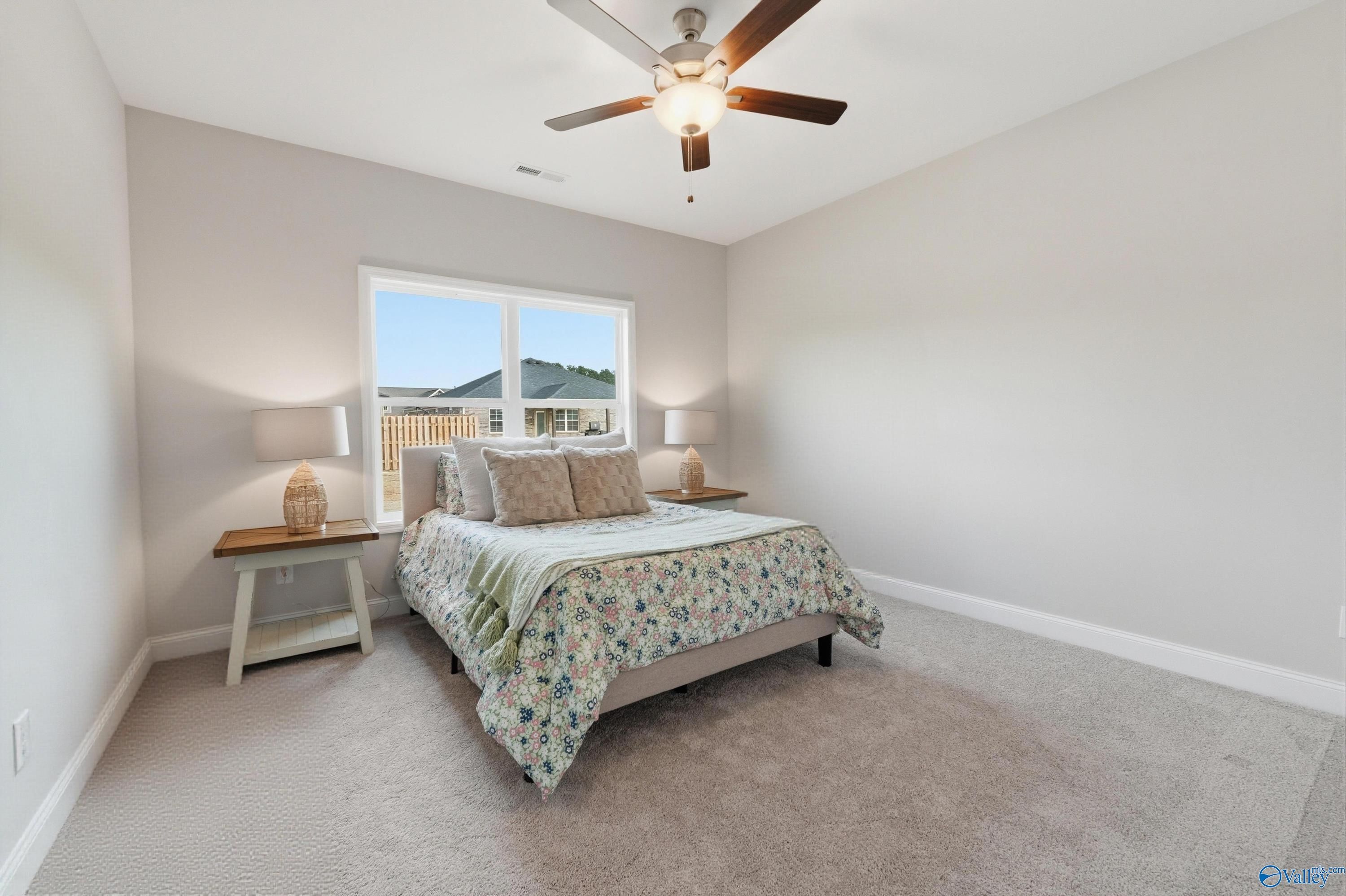 Bright bedroom with ceiling fan, large window, queen bed, and nightstands in Davidson Homes The Asheville, Toney, Alabama