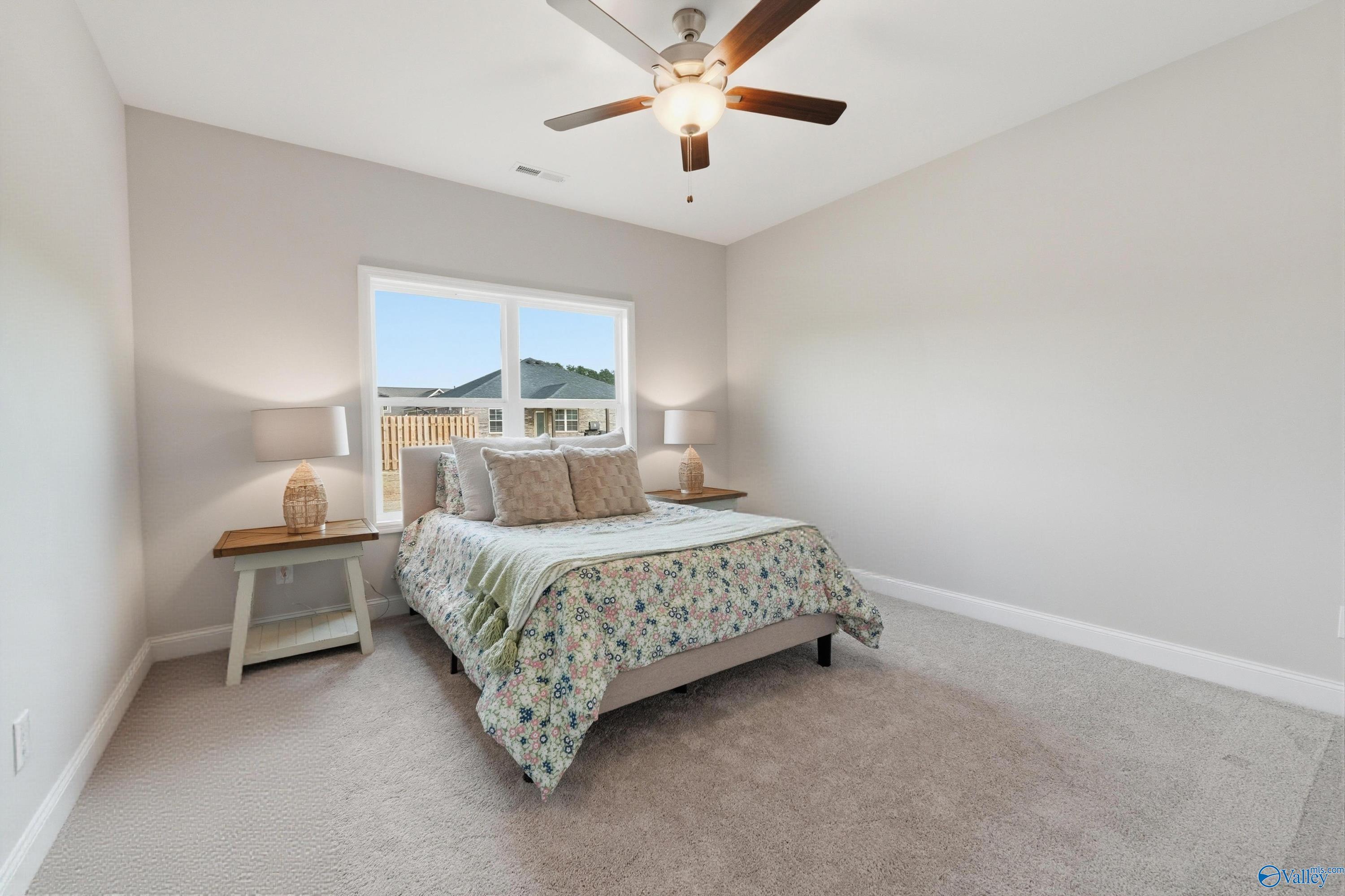 Bright bedroom with ceiling fan, large window, queen bed, and nightstands in Davidson Homes The Asheville, Toney, Alabama