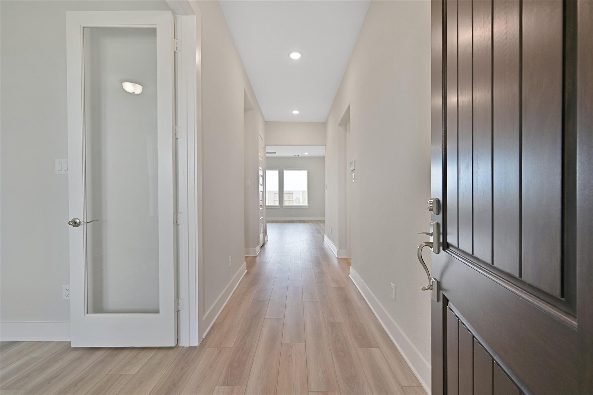 Elegant entry hallway with hardwood floors, beige walls, and recessed lights in Davidson Homes The Edward A, Lago Mar, Texas City