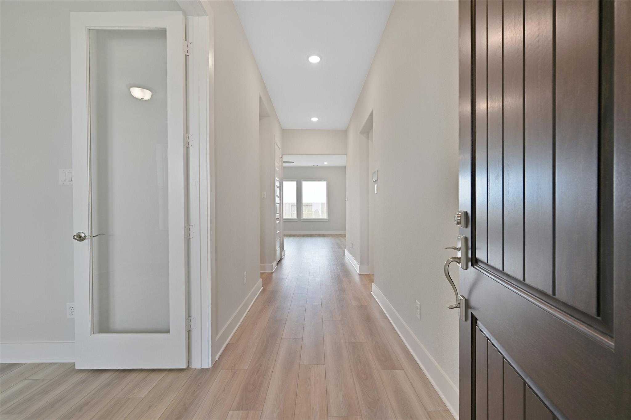 Bright hallway with oak hardwood floors, glass-paneled door, and recessed lights in Davidson Homes The Edward A, Lago Mar, Texas City, Texas