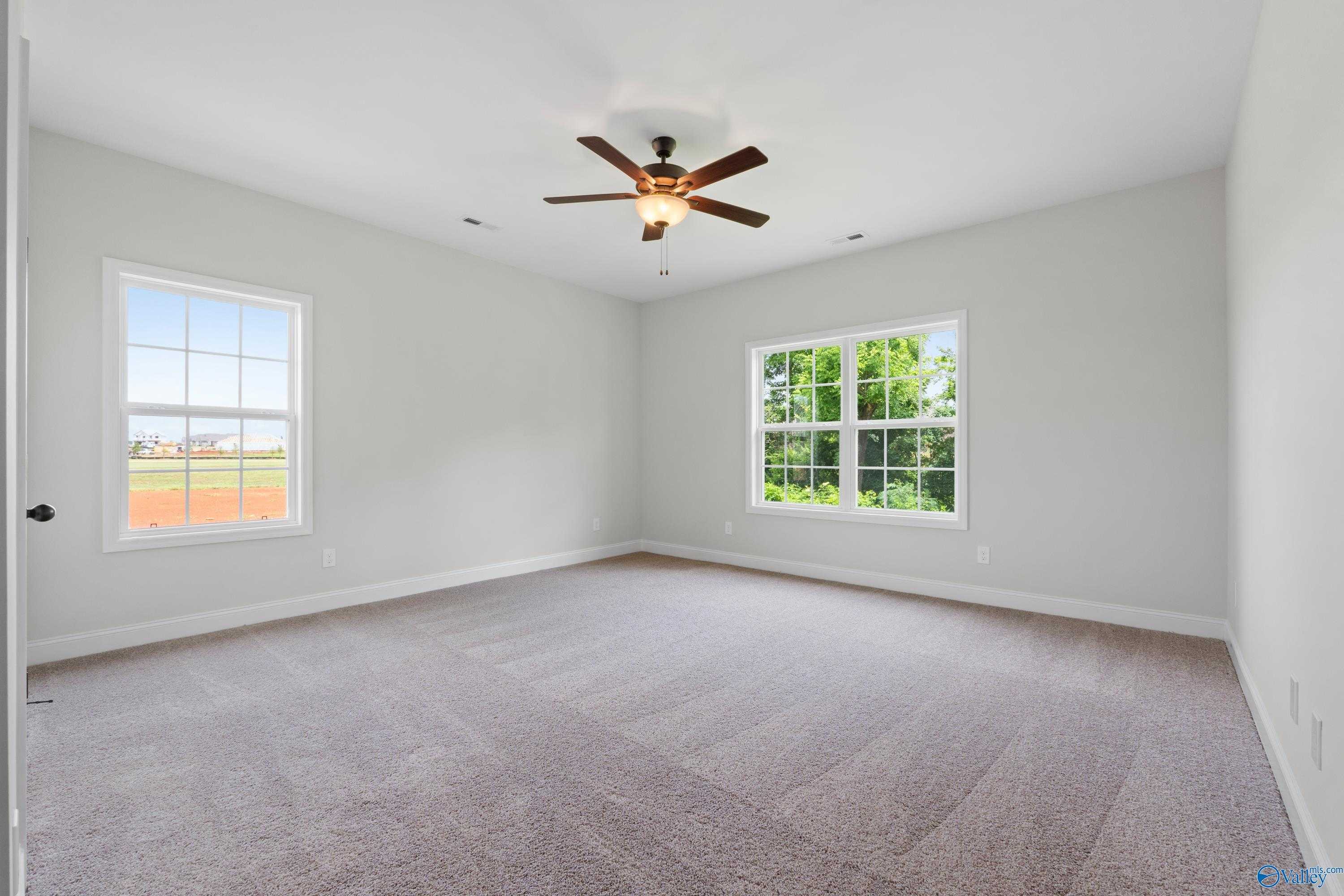 Spacious secondary bedroom with ceiling fan, large windows overlooking trees and baseball field in Davidson Homes The Kirkland, Harvest AL