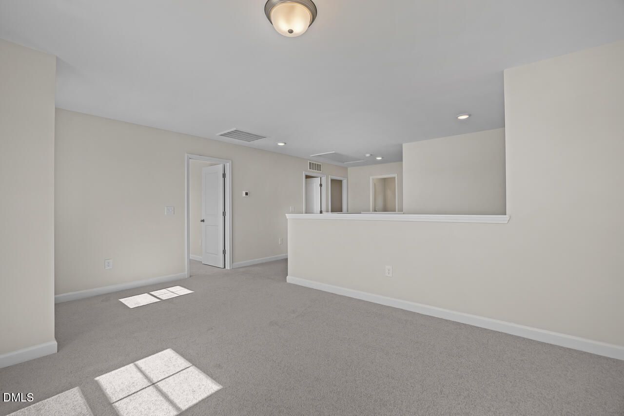 Spacious carpeted upstairs loft with half wall and natural light in Davidson Homes The Willow C, Woodland Crossing, Zebulon NC