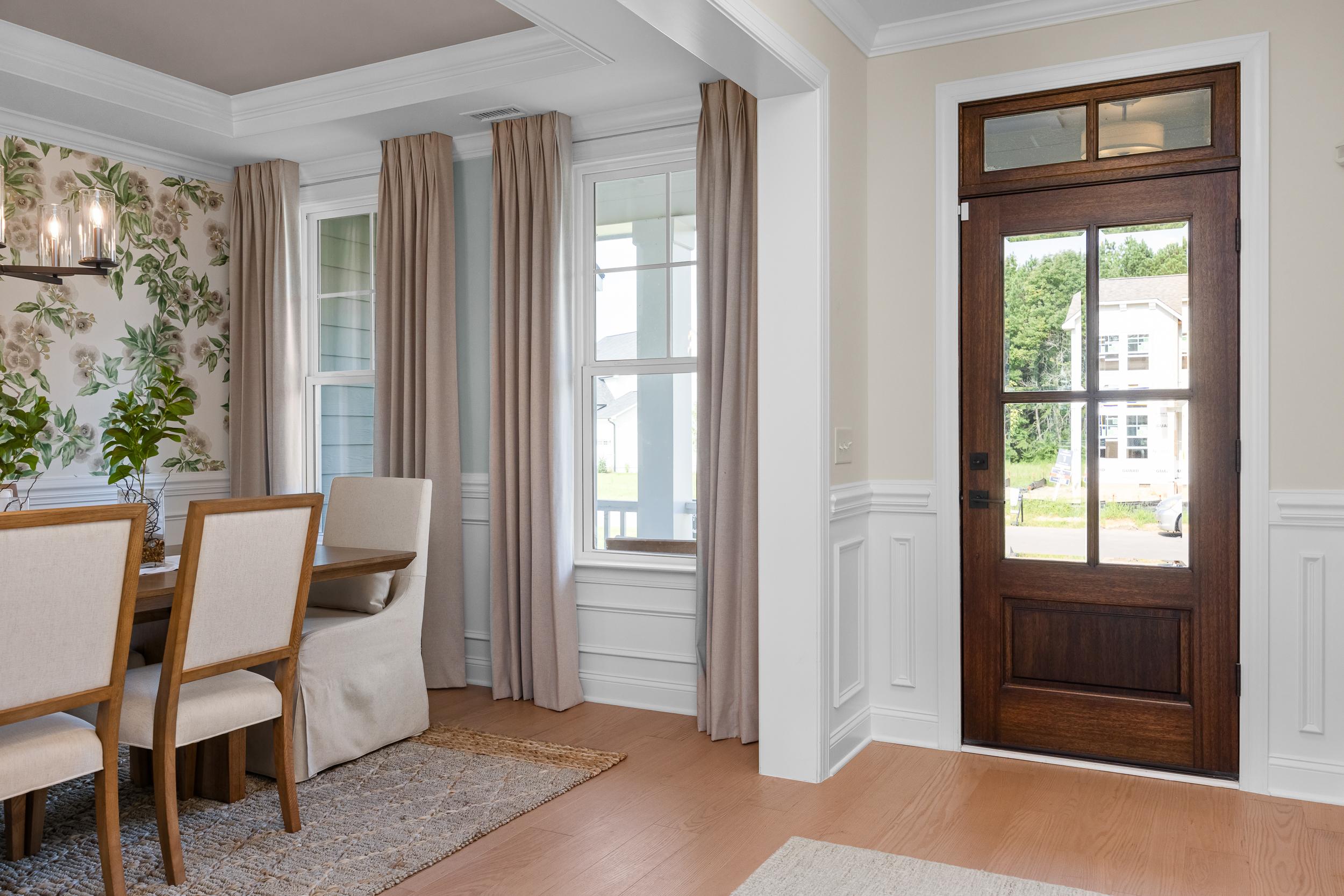 Elegant dining room at Laneridge Estates in Raleigh, NC with wooden table, floral wallpaper, beige curtains, and hardwood floors