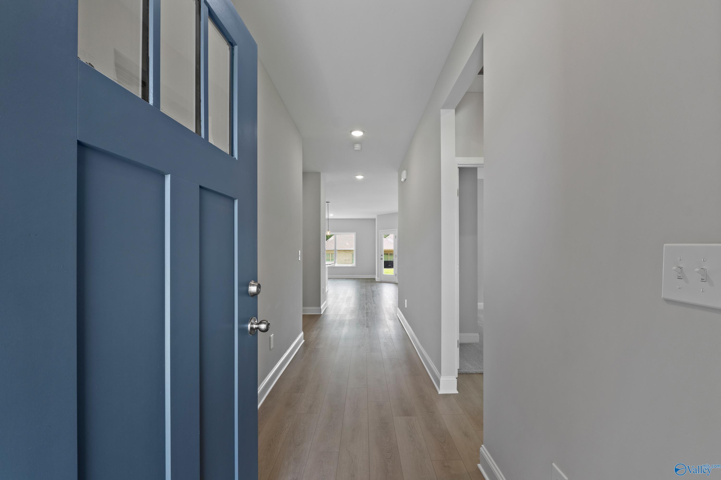 Welcoming navy blue front door opening to hardwood hallway in 3-bedroom Davidson Homes The Franklin C, Durham Farms, Harvest, Alabama