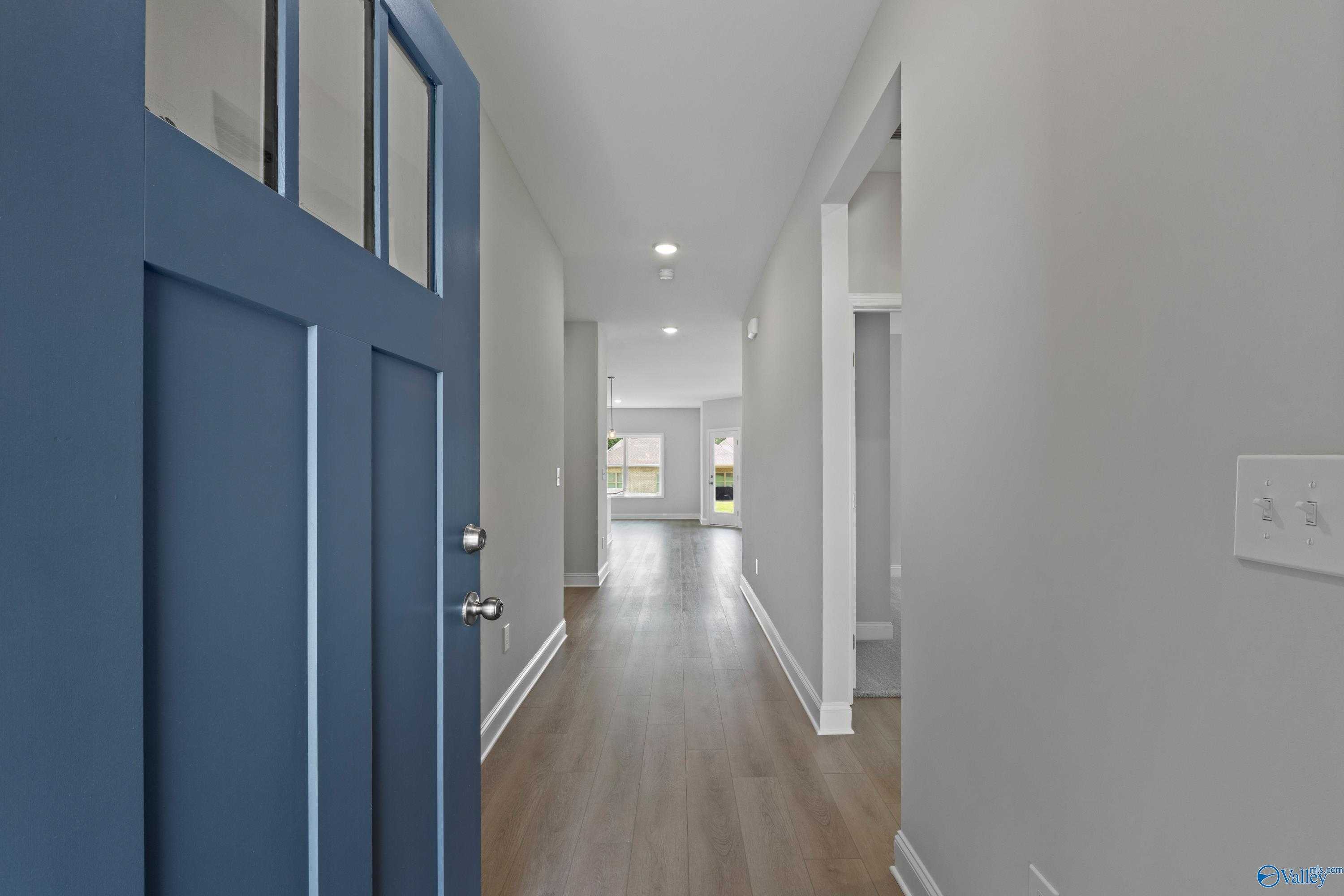 Welcoming navy blue front door opening to hardwood hallway in 3-bedroom Davidson Homes The Franklin C, Durham Farms, Harvest, Alabama