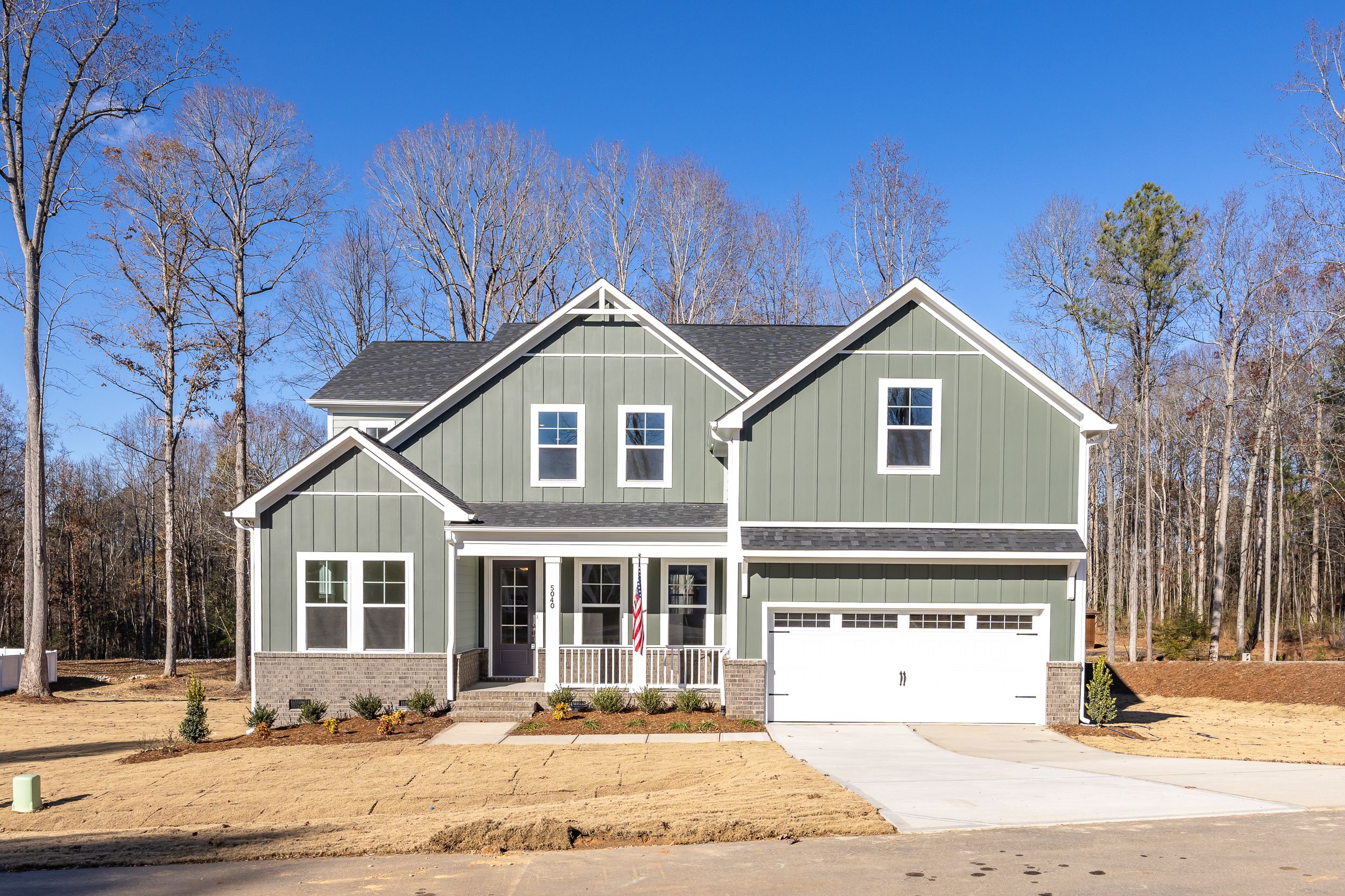 Modern farmhouse home exterior at Ashland in Apex, NC with covered porch, board-and-batten siding, and two-car garage