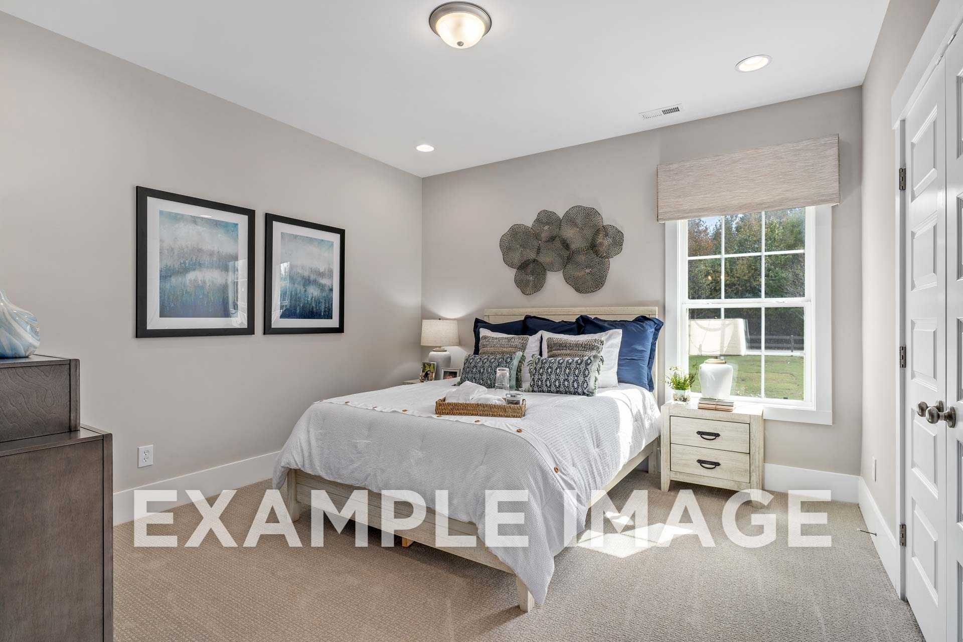 Spacious secondary bedroom in The Harrison D by Davidson Homes, Athens AL: white bed with blue pillows, nightstands, wall art, large window