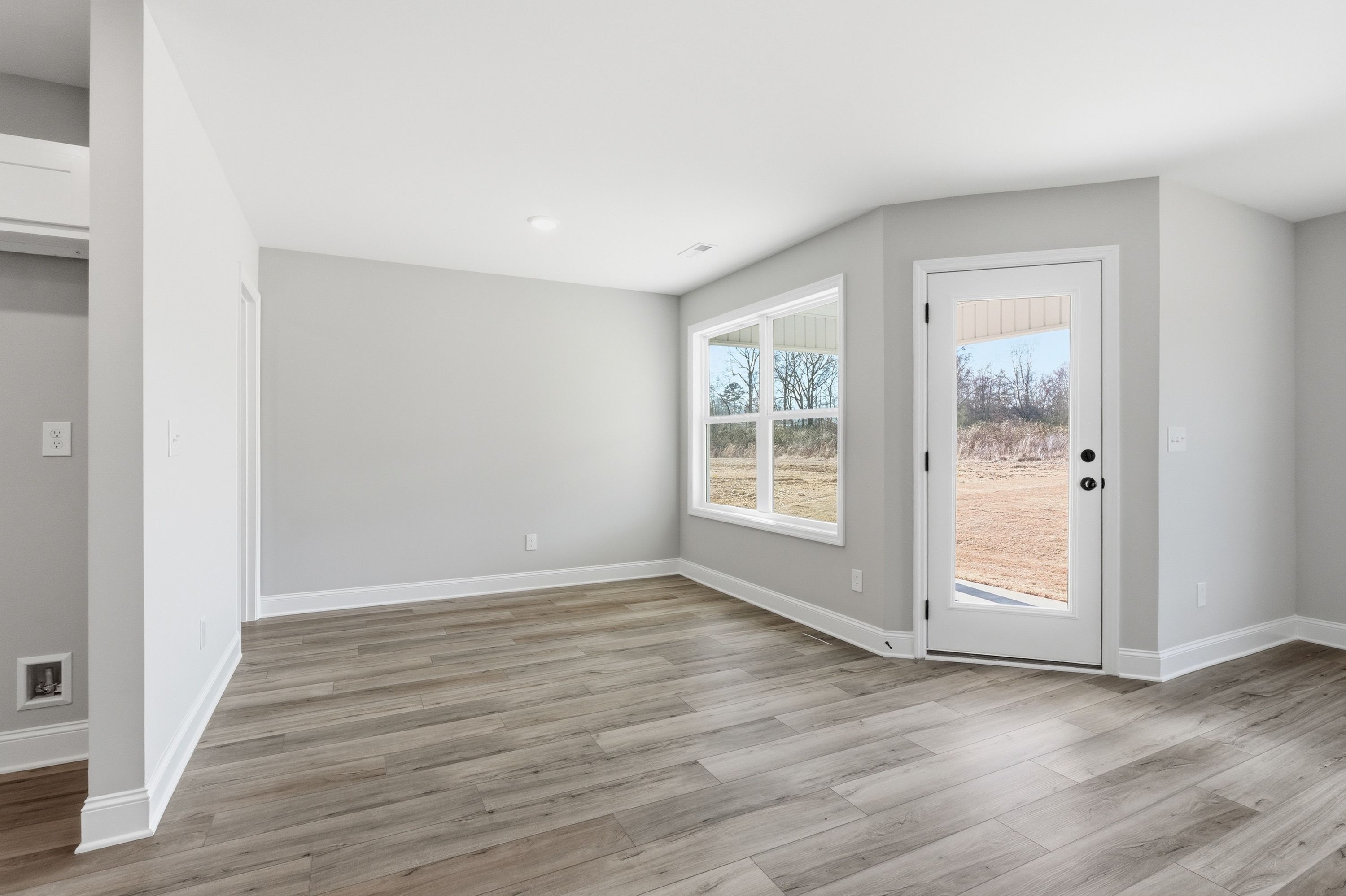 Spacious master bedroom in The Daphne V with gray walls, large windows, French door, and light wood floors