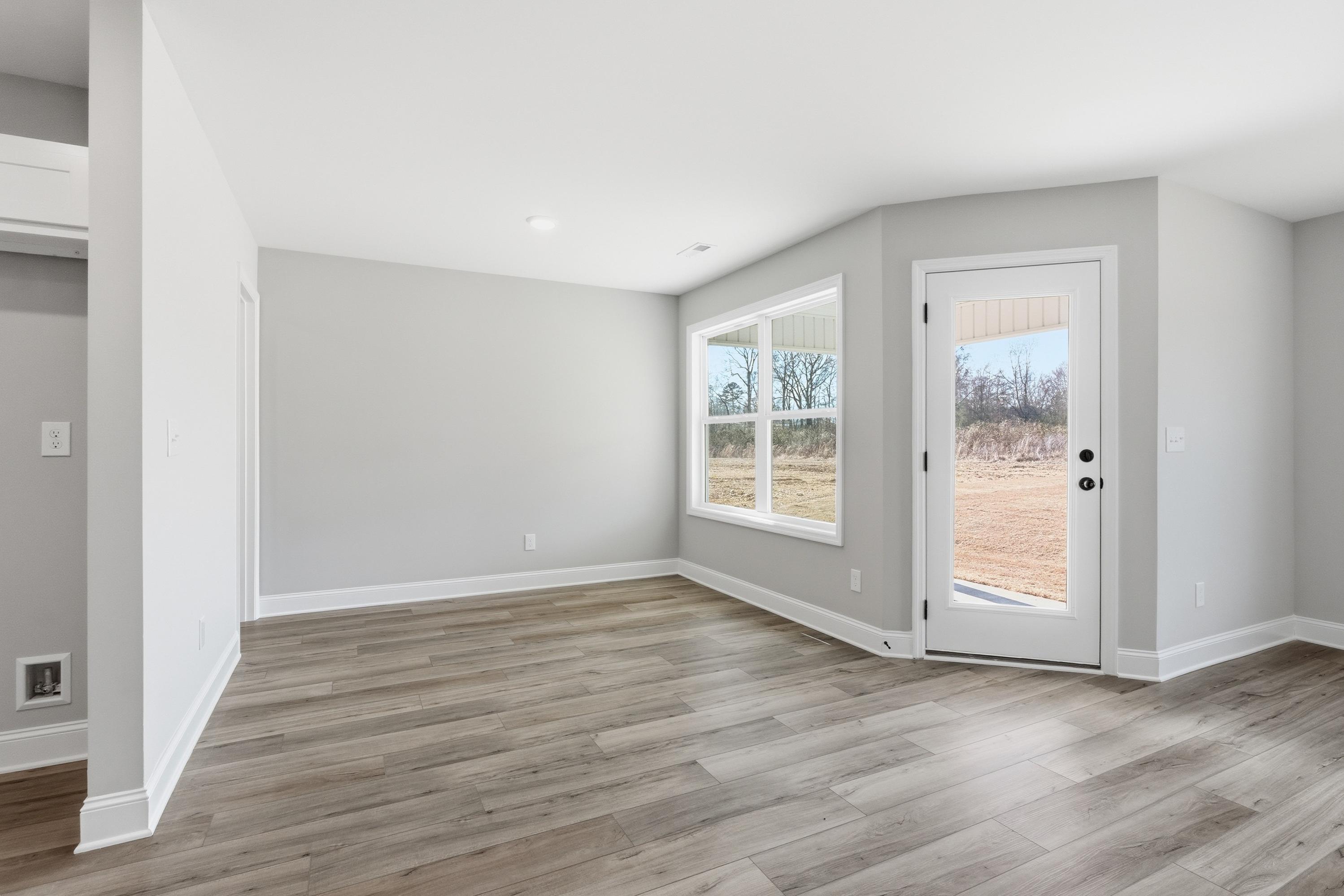 Spacious master bedroom in The Daphne V with gray walls, large windows, French door, and light wood floors