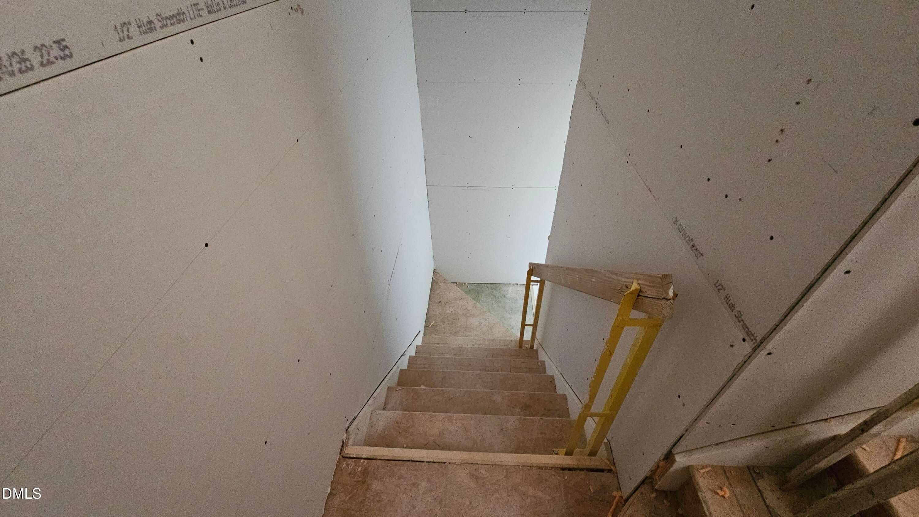 Unfinished wooden staircase with temporary handrail inside The Graham floor plan at Springvale, Fuquay-Varina, NC.