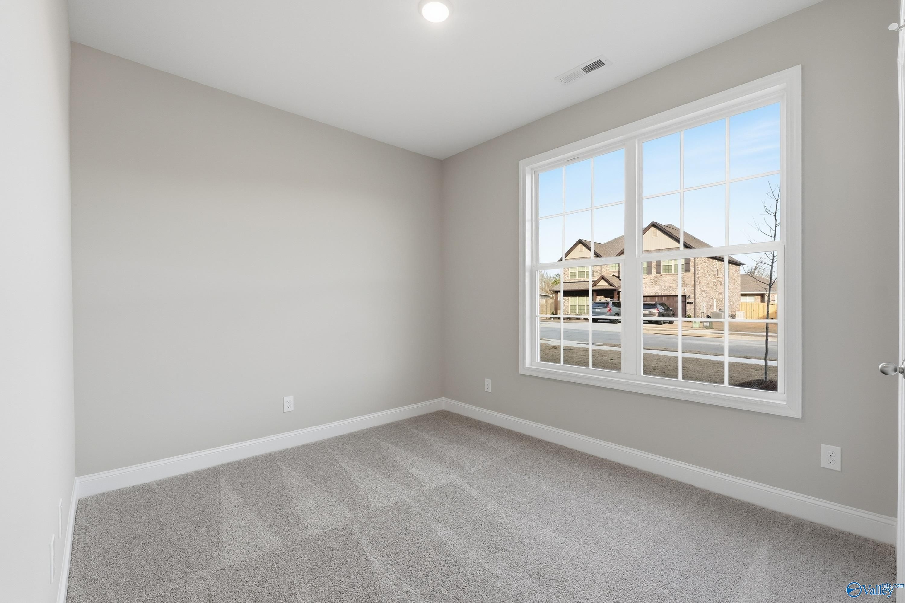 Cozy bedroom with light gray walls, large window overlooking neighborhood in Davidson Homes The Asheville, Arab, Alabama