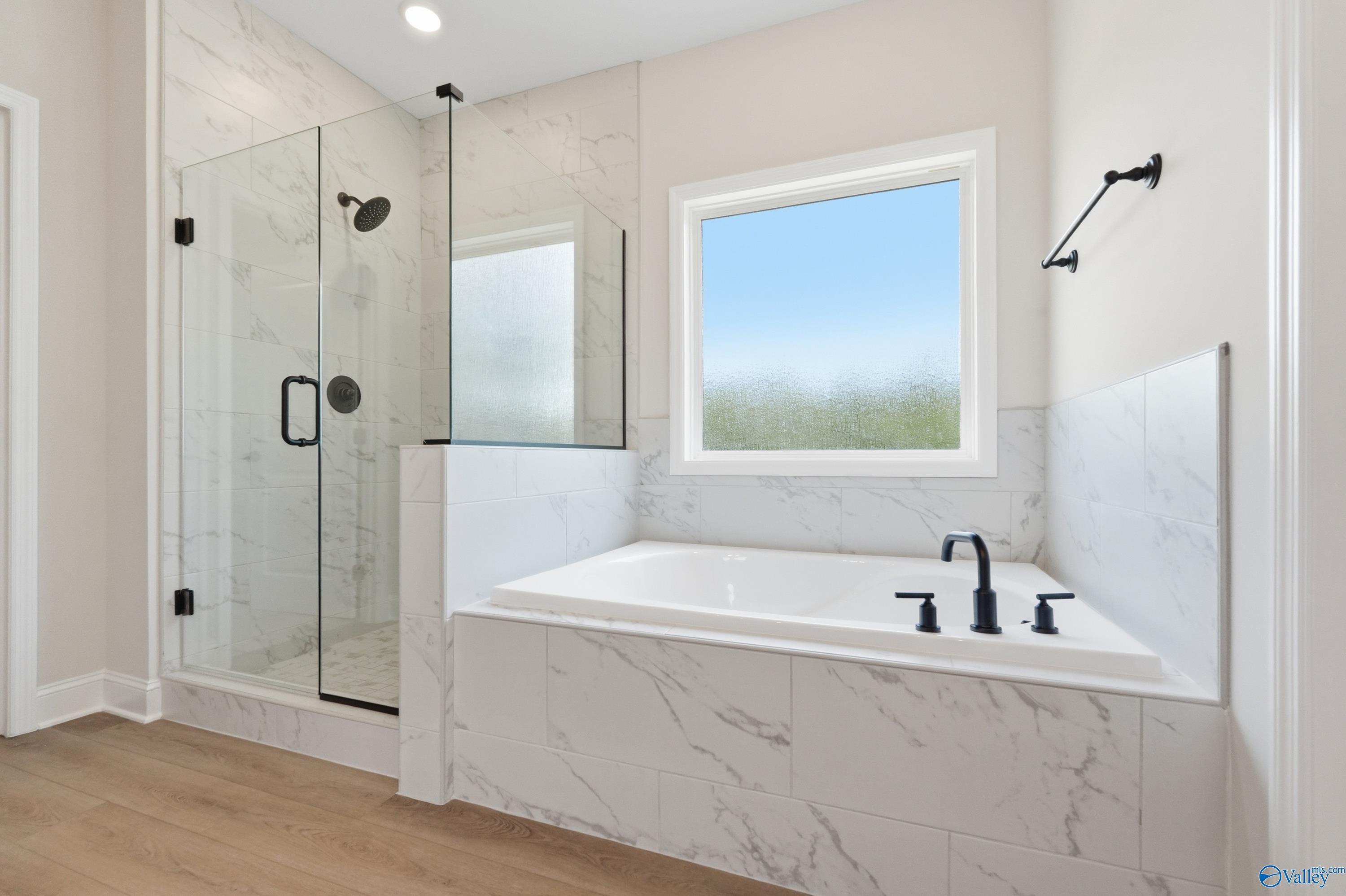 Elegant master bathroom with marble tiles, frameless glass shower, soaking tub in Davidson Homes The Rockford B, Athens AL