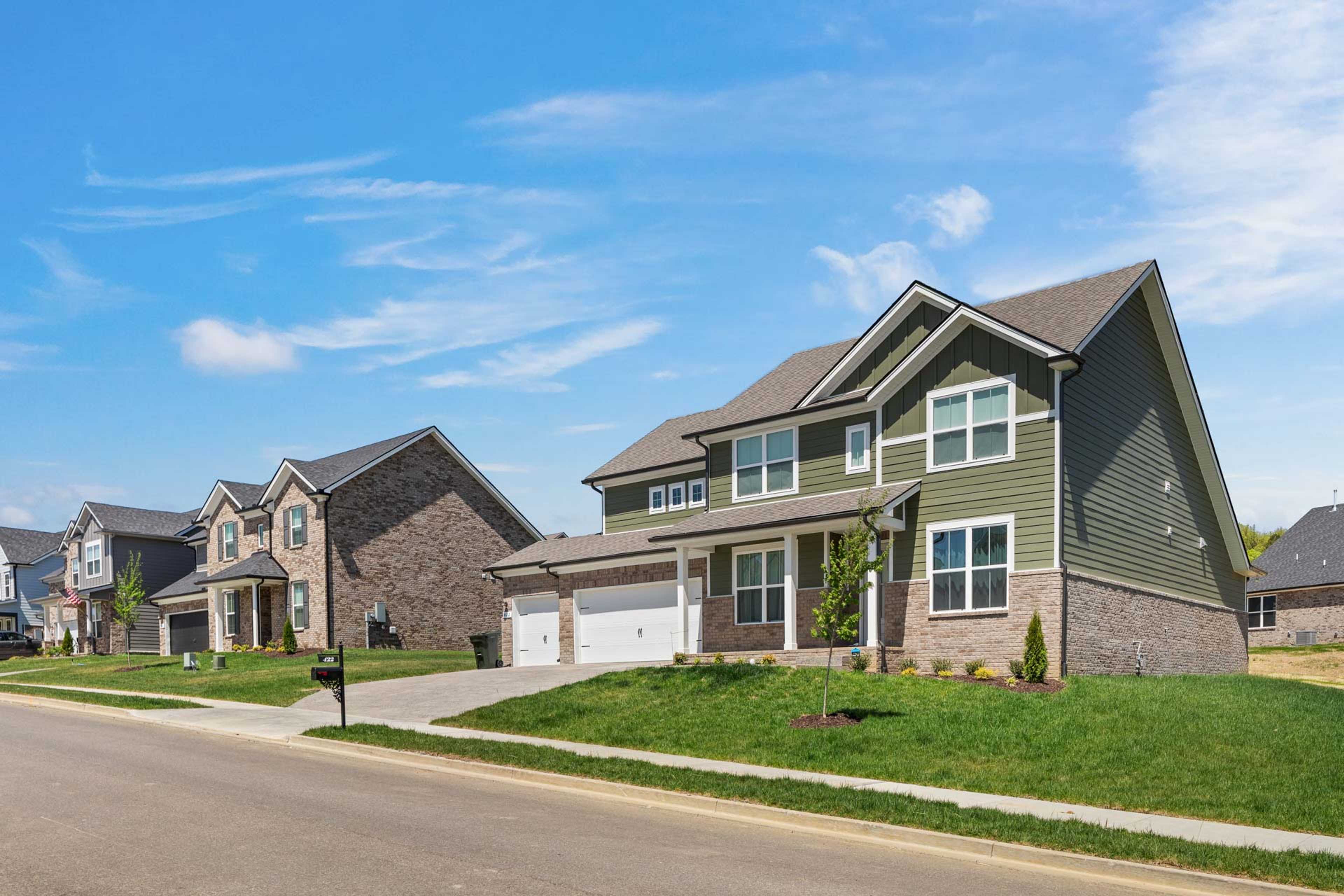 Contemporary two-story homes in Carellton, Gallatin TN by Davidson Homes with sage green siding, brick accents, and manicured lawns