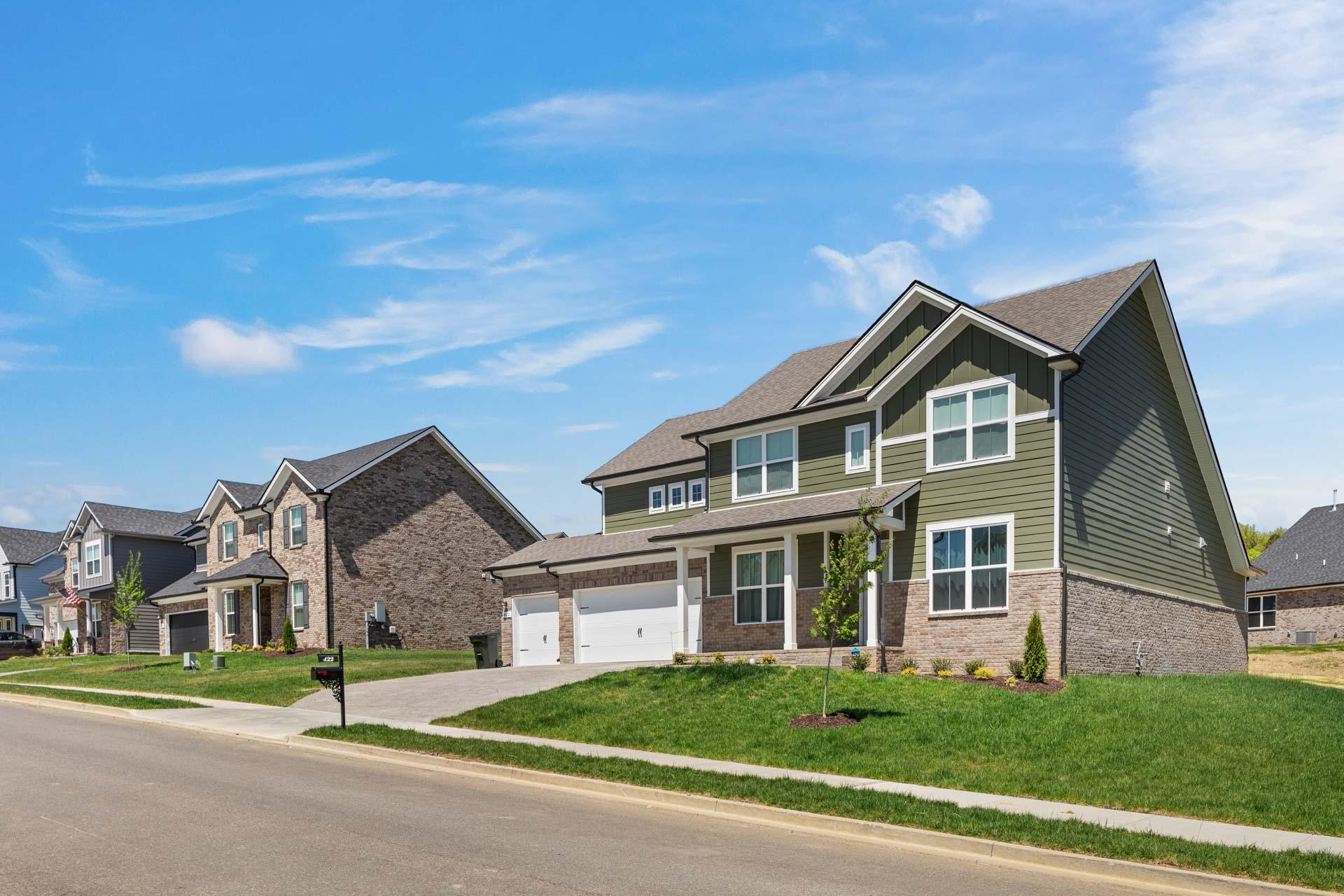 Contemporary two-story homes in Carellton, Gallatin TN by Davidson Homes with sage green siding, brick accents, and manicured lawns