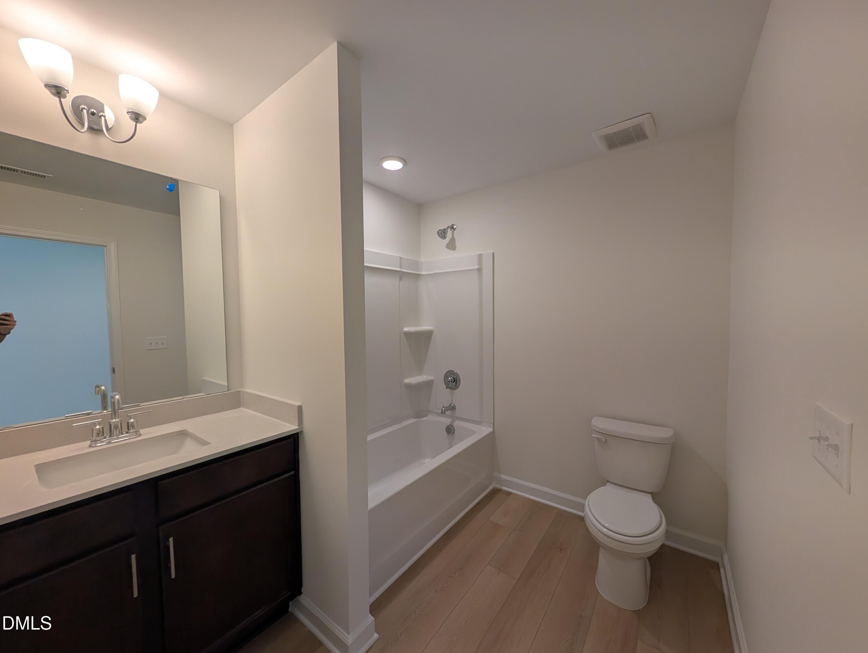 Full bathroom with tub-shower combo, dark wood vanity, and hardwood floors in Davidson Homes Magnolia A, Wendell Ridge NC