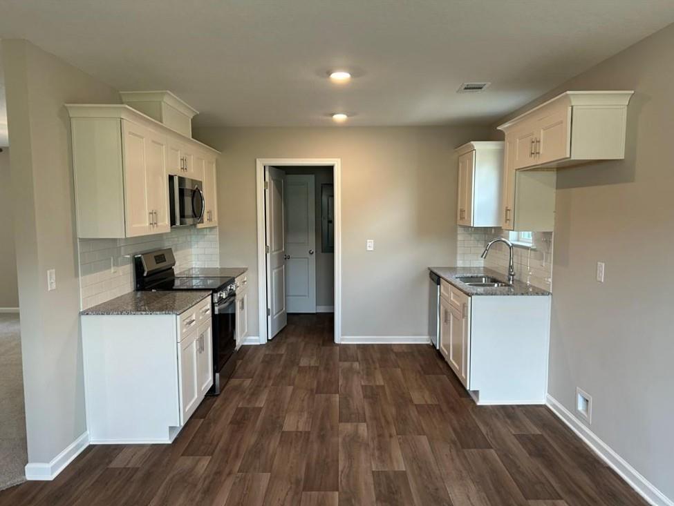 Modern white cabinet kitchen with granite counters, stainless appliances, and hardwood floors in The Washington Davidson Homes, Phenix City