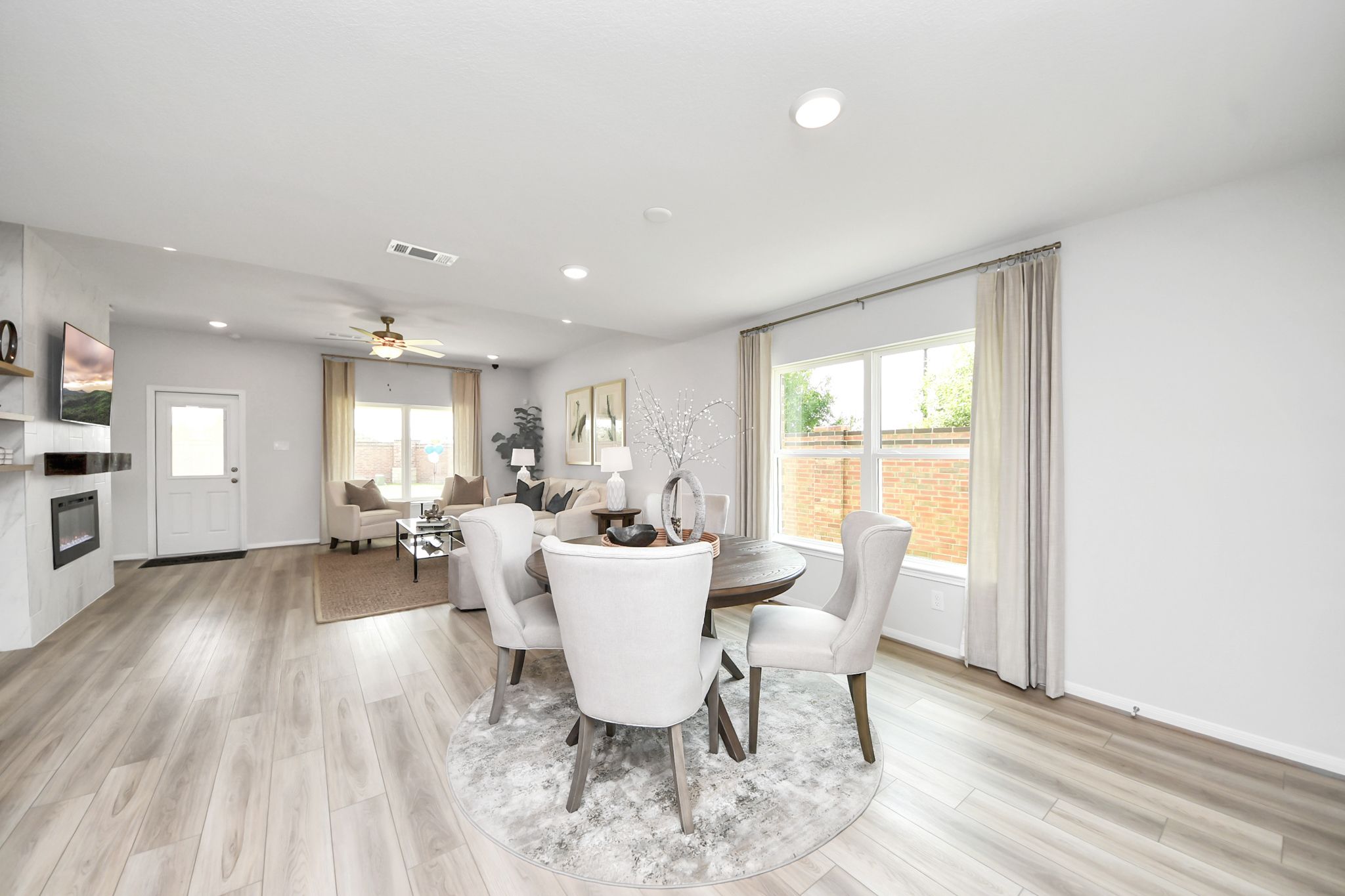 Open-concept dining and living area by Davidson Homes at Sunterra in Katy, TX with modern decor and wood-look flooring.