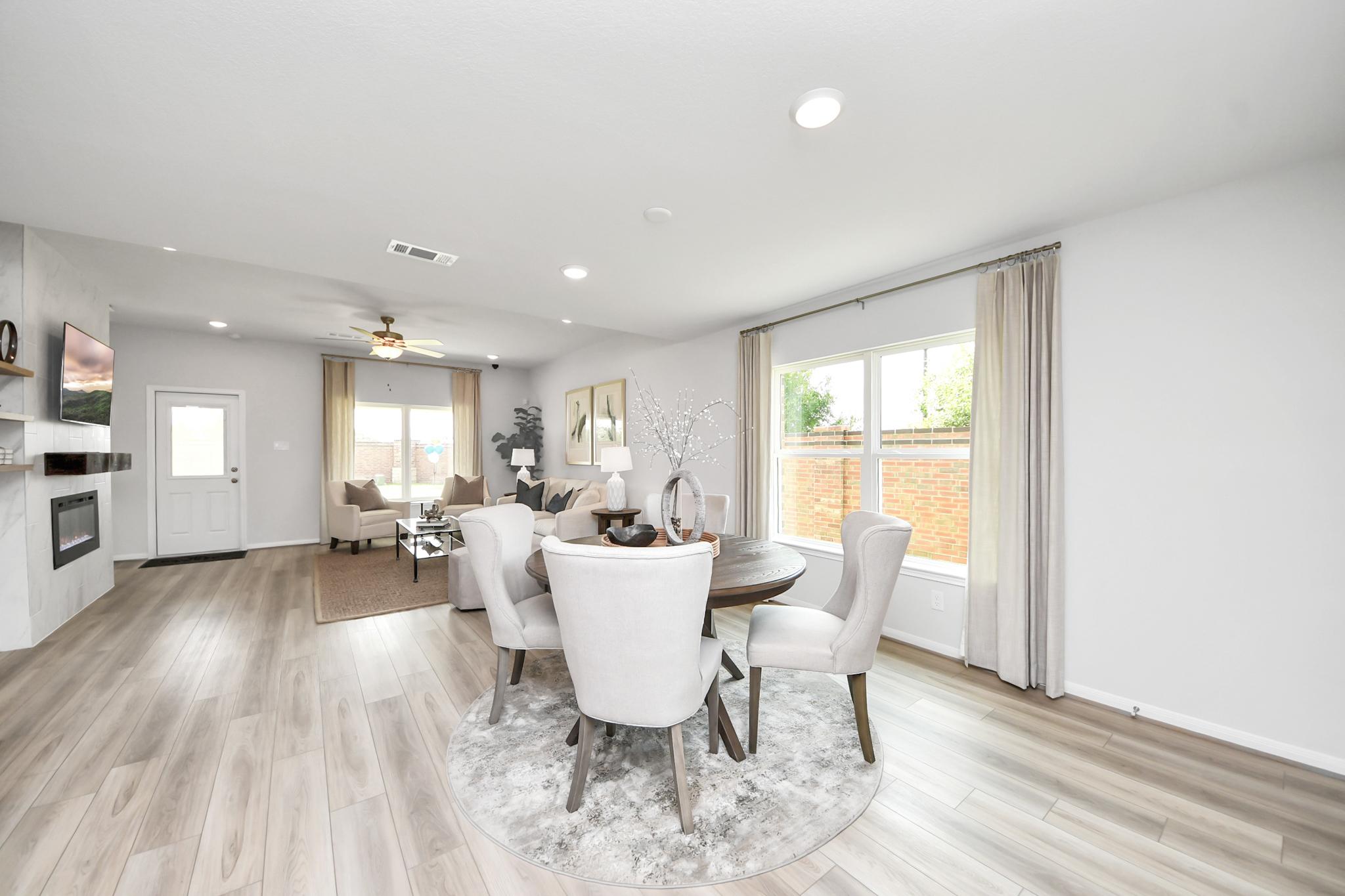 Open-concept dining and living area by Davidson Homes at Sunterra in Katy, TX with modern decor and wood-look flooring.