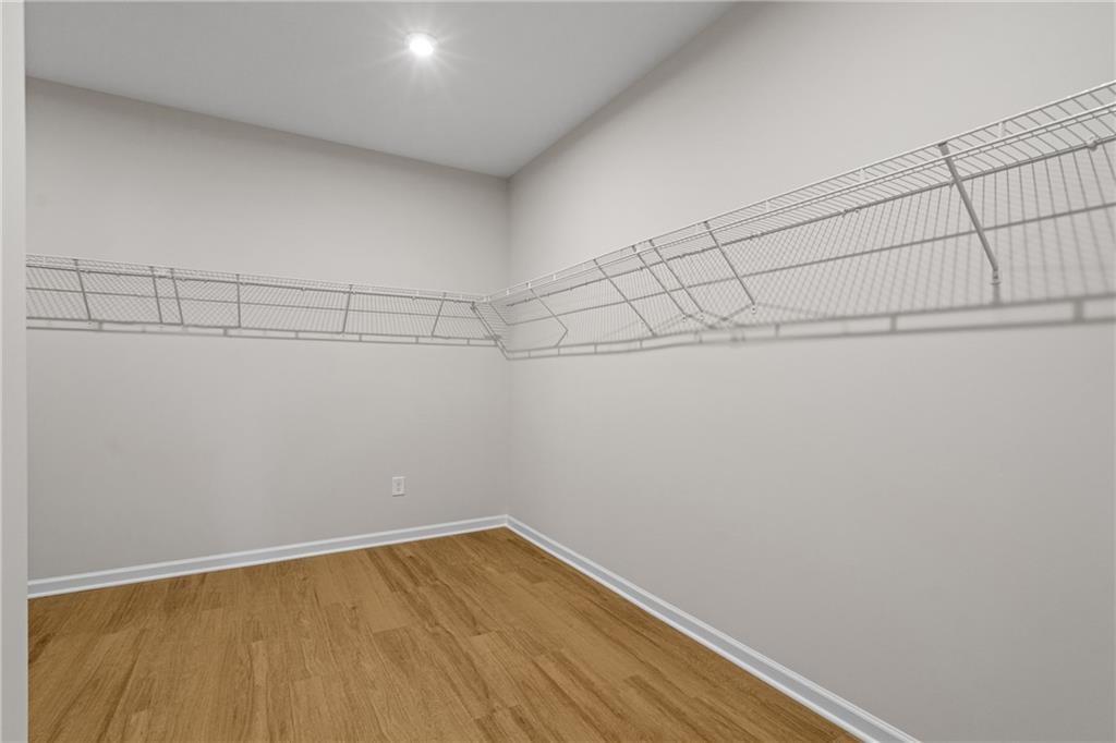 Walk-in closet with wire shelving on neutral walls, hardwood floors in Davidson Homes The Edison B, Kelly Preserve, Loganville, GA