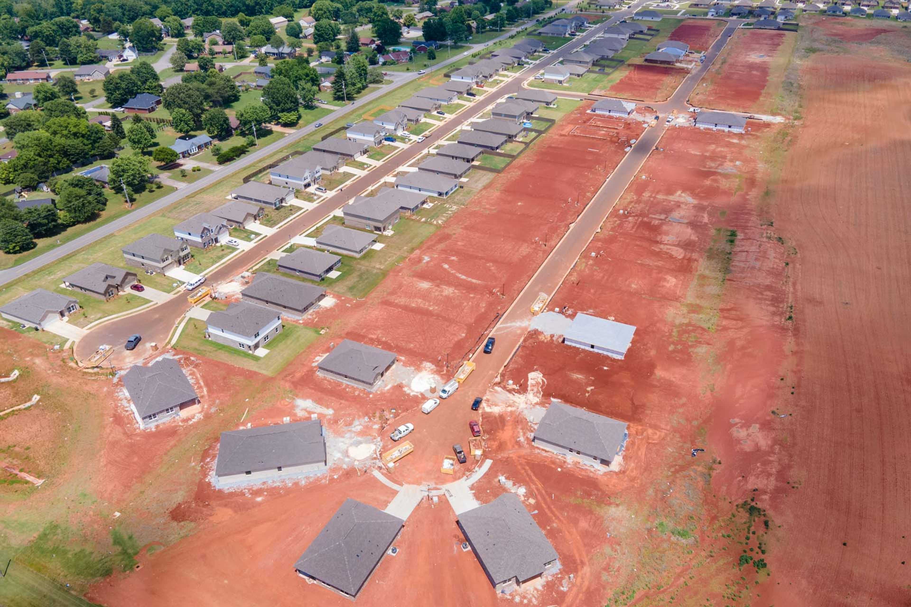 Aerial view of new home construction at Clearview in Hazel Green Alabama with red clay soil, partial house frames and surrounding greenery