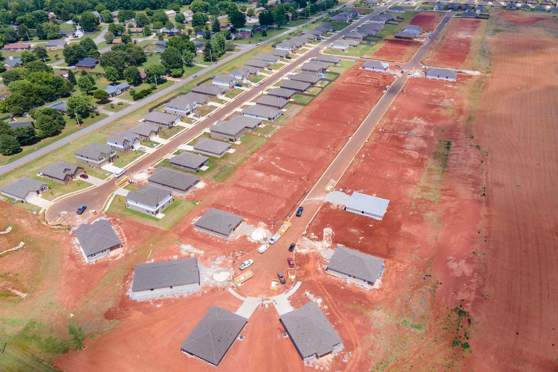 Aerial view of new home construction at Clearview in Hazel Green Alabama with red clay soil, partial house frames and surrounding greenery