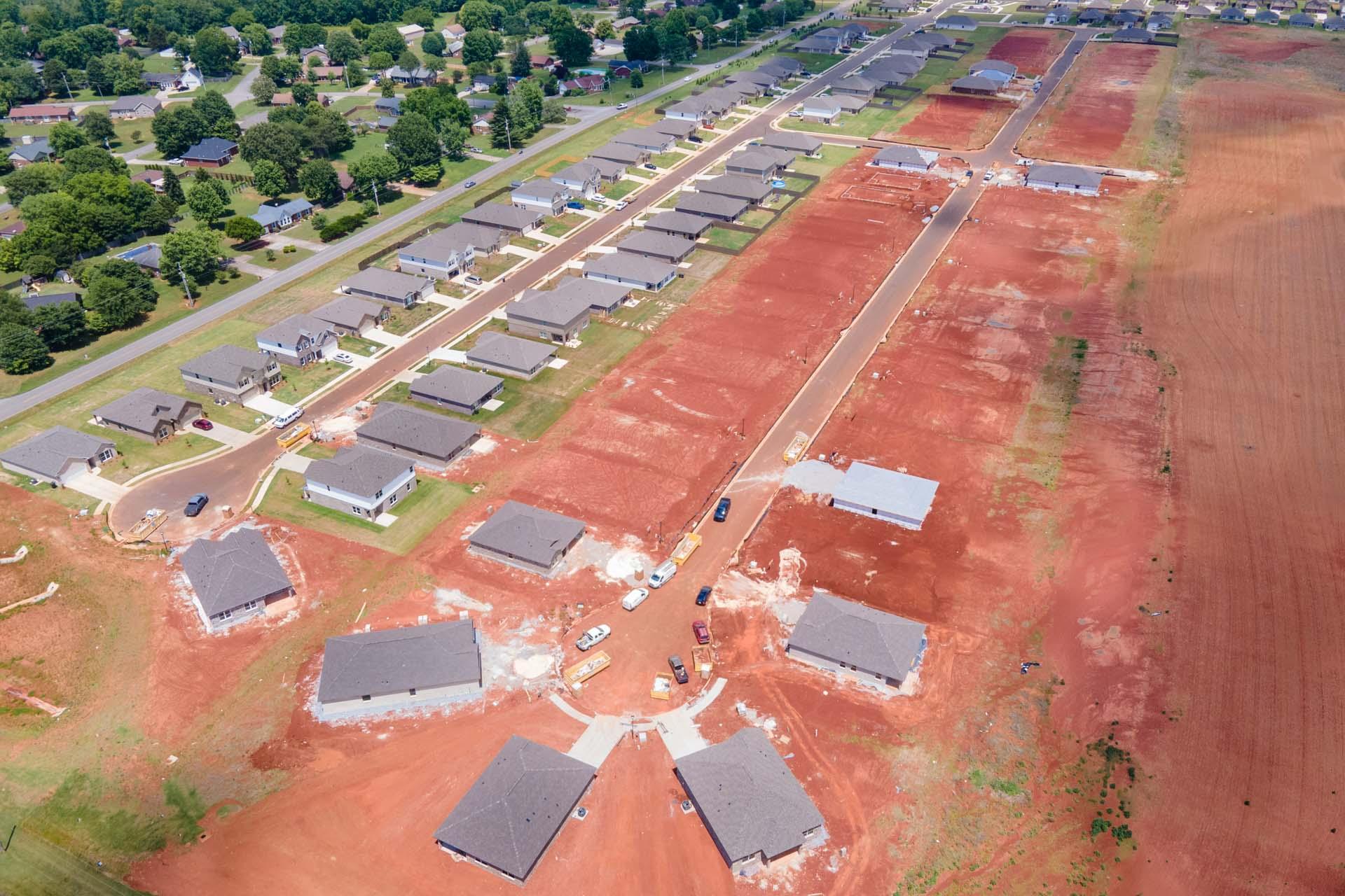 Aerial view of new home construction at Clearview in Hazel Green Alabama with red clay soil, partial house frames and surrounding greenery