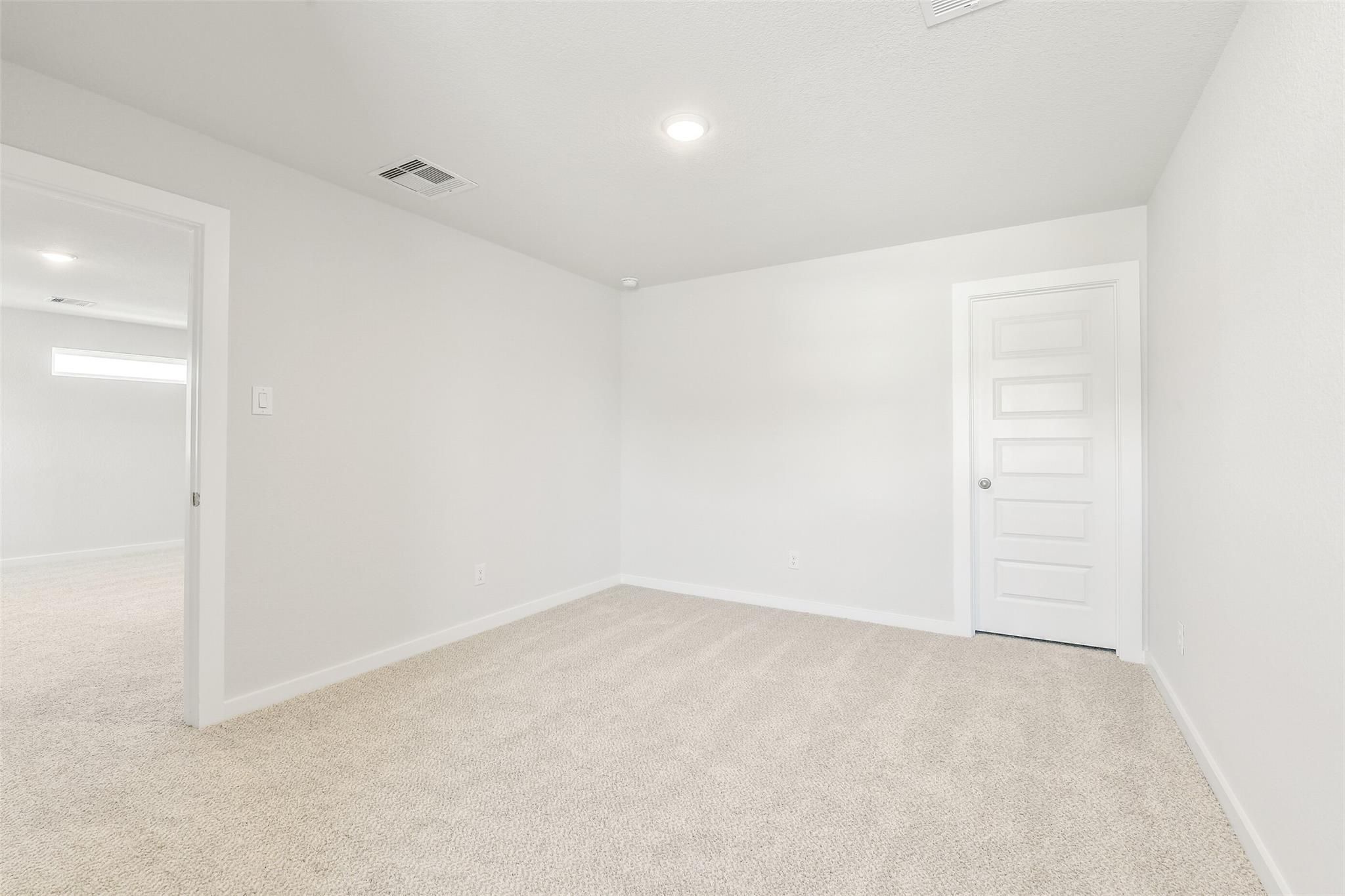 Spacious empty bedroom with beige carpet and white walls in Davidson Homes San Marcos E, Cleveland Texas