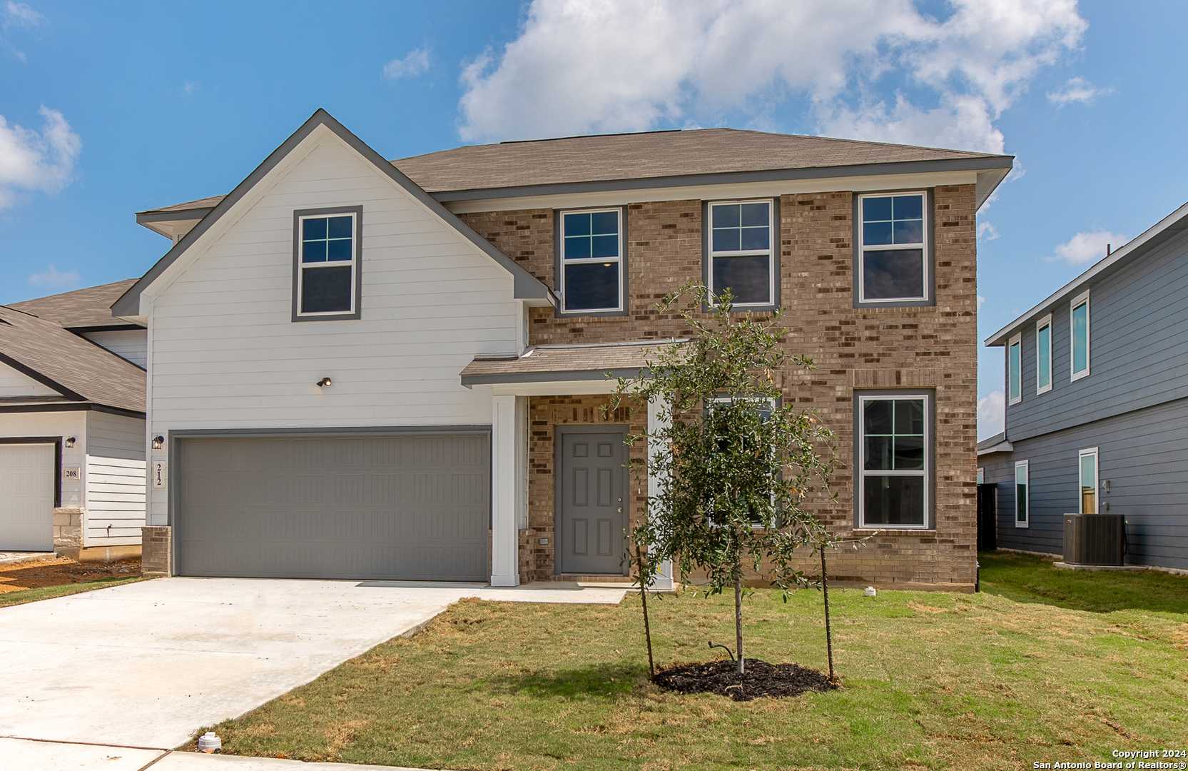 2-story Davidson Homes Murray H exterior with brick and white siding, 2-car garage, front door, young tree, and driveway in Hannah Heights, Seguin, Texas
