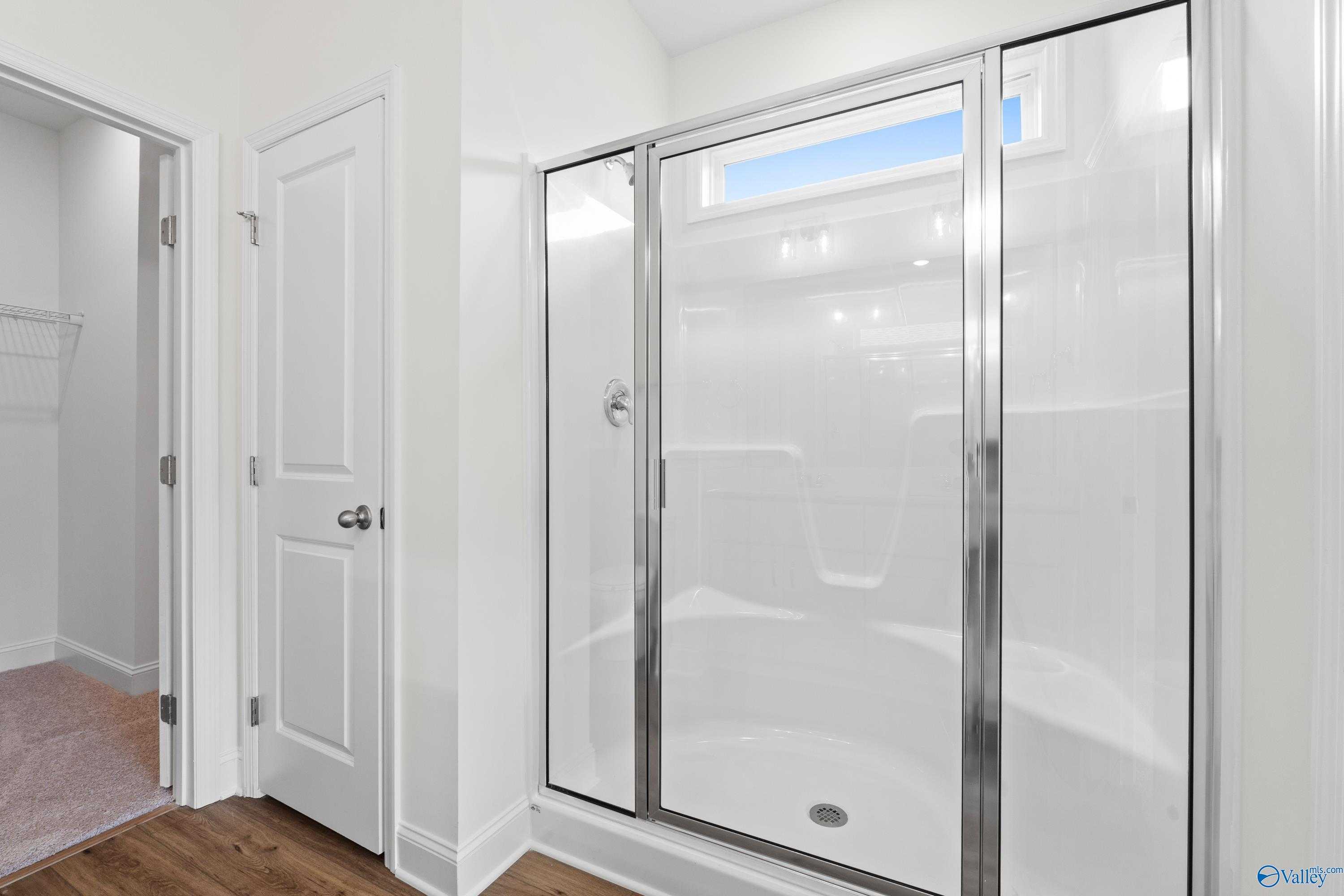 Modern frameless glass shower with white subway tile and clerestory window in Davidson Homes The Asheville C, Athens, Alabama