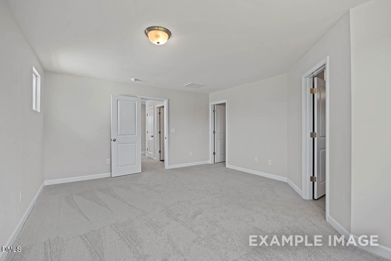 Spacious carpeted bedroom with neutral walls in The Graham floor plan at Springvale, Fuquay-Varina, North Carolina.