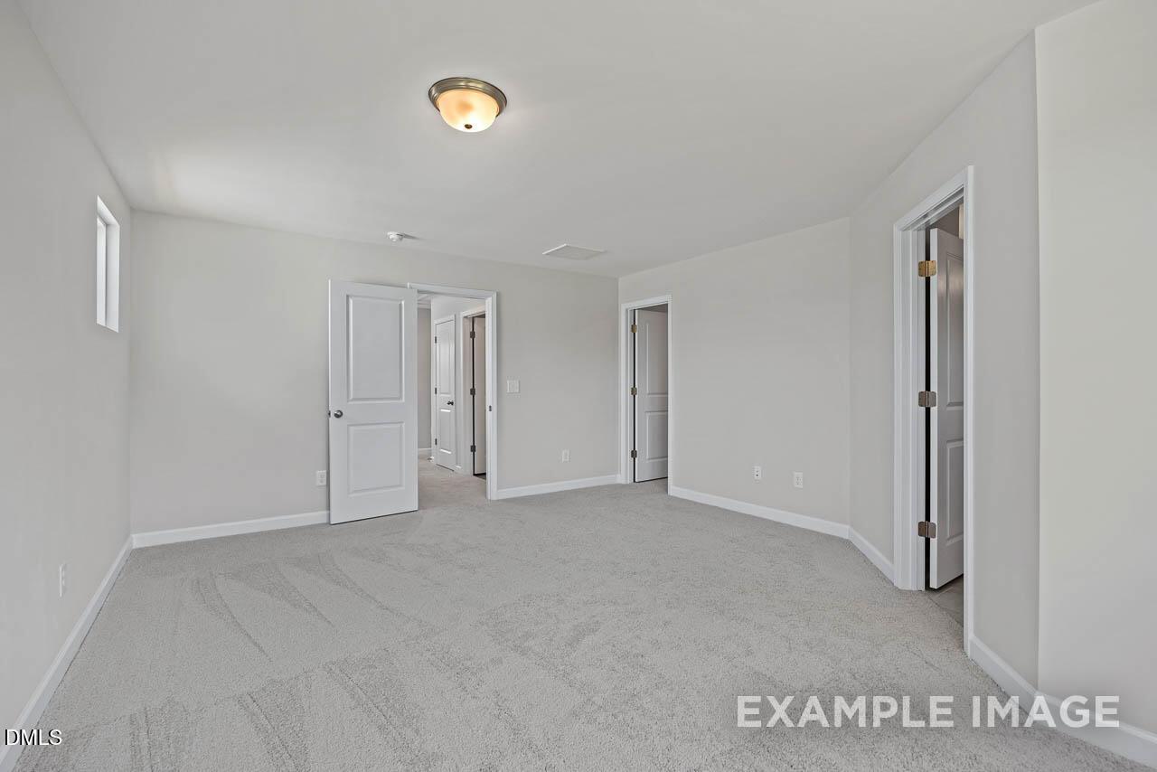 Spacious carpeted bedroom with neutral walls in The Graham floor plan at Springvale, Fuquay-Varina, North Carolina.