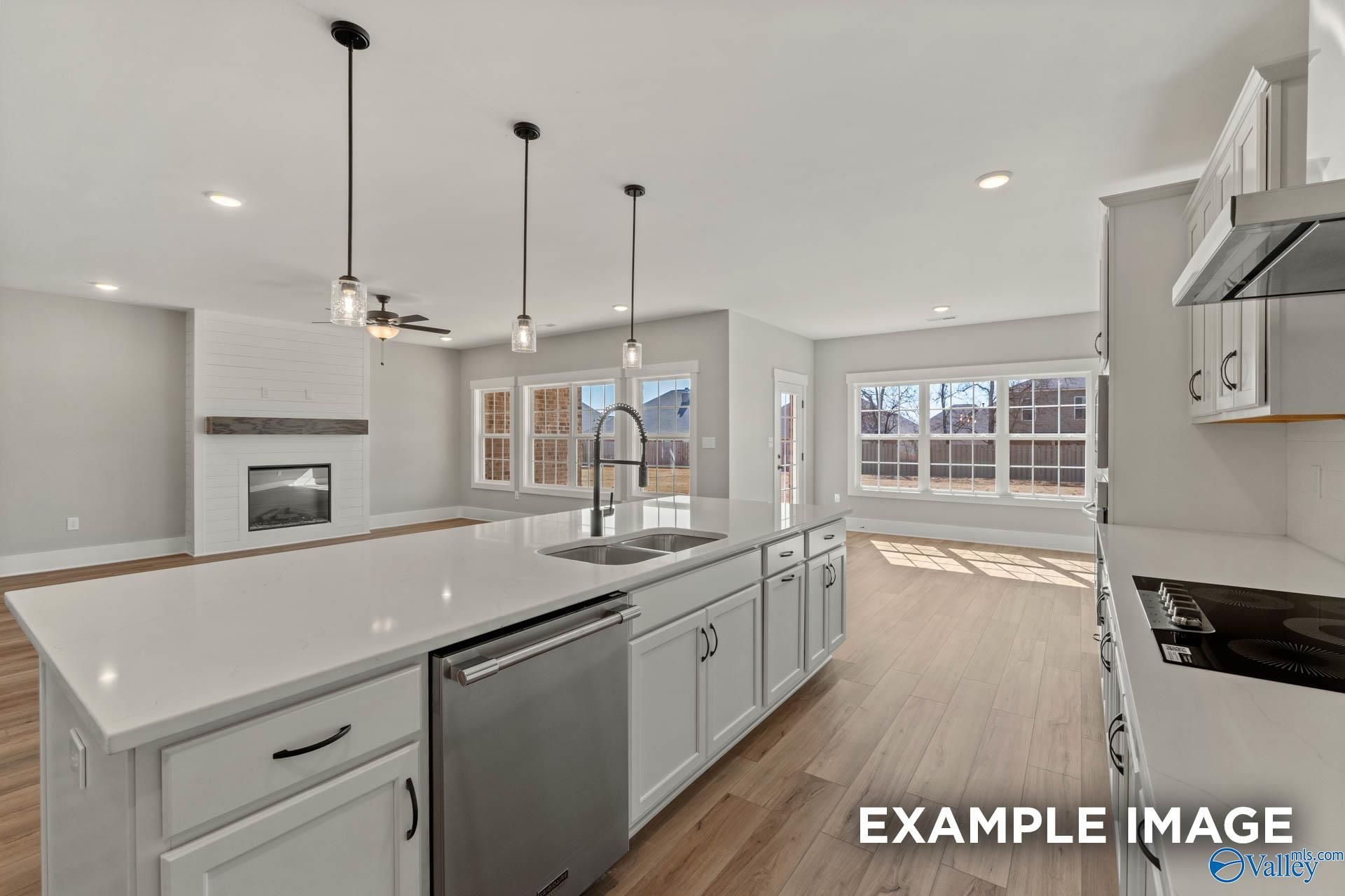 Open-concept kitchen with white island and shiplap fireplace in The Finleigh floor plan at Briercreek, Meridianville, AL.