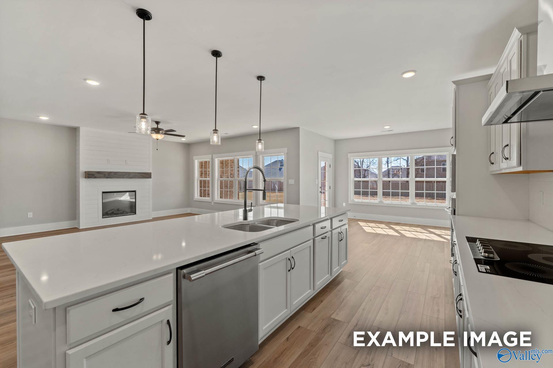 Open-concept kitchen with white island and shiplap fireplace in The Finleigh floor plan at Briercreek, Meridianville, AL.
