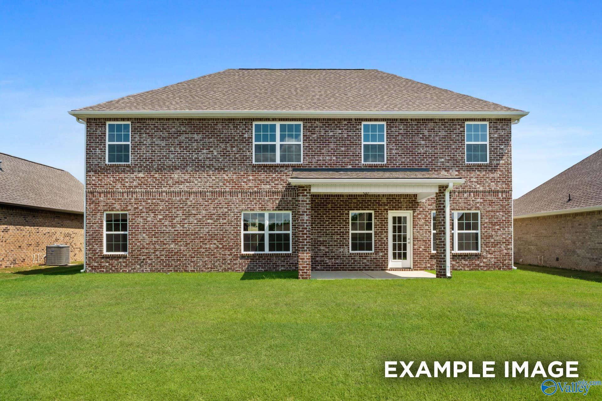 Rear view of two-story brick Davidson Homes Madison A with covered patio, French doors, and lush green yard in Pikes Ridge, Meridianville, Alabama