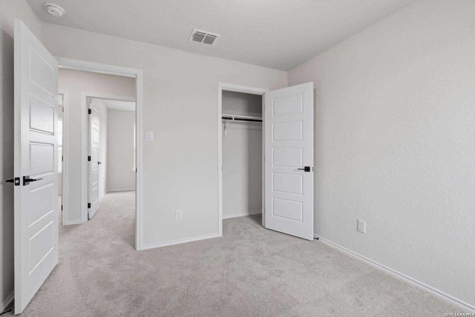 Spacious secondary bedroom with open walk-in closet, beige walls, and gray carpet in Davidson Homes The Blanco C, San Antonio