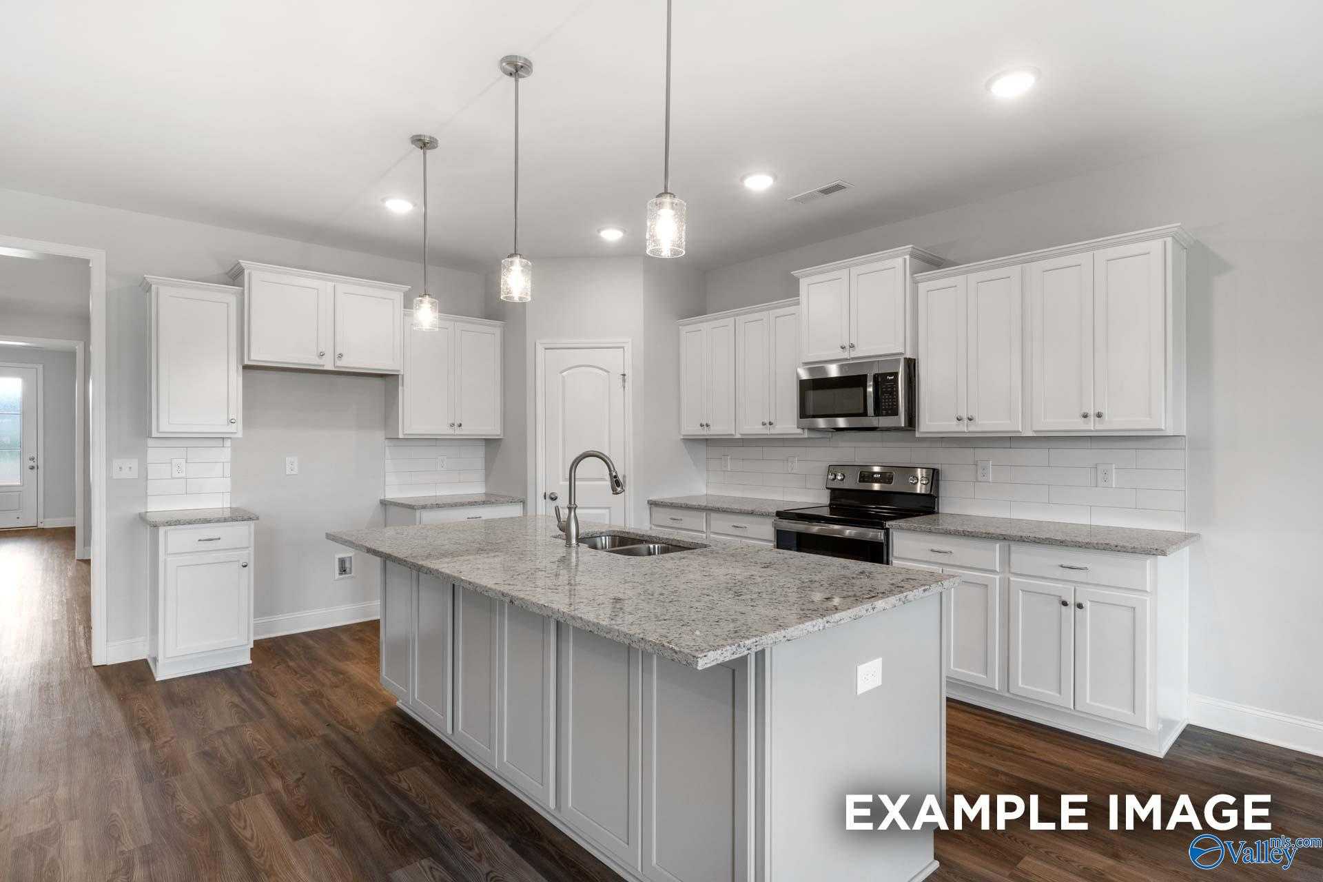 Modern white kitchen with granite island, stainless appliances, pendant lights in Davidson Homes The Harrison B, Decatur, AL