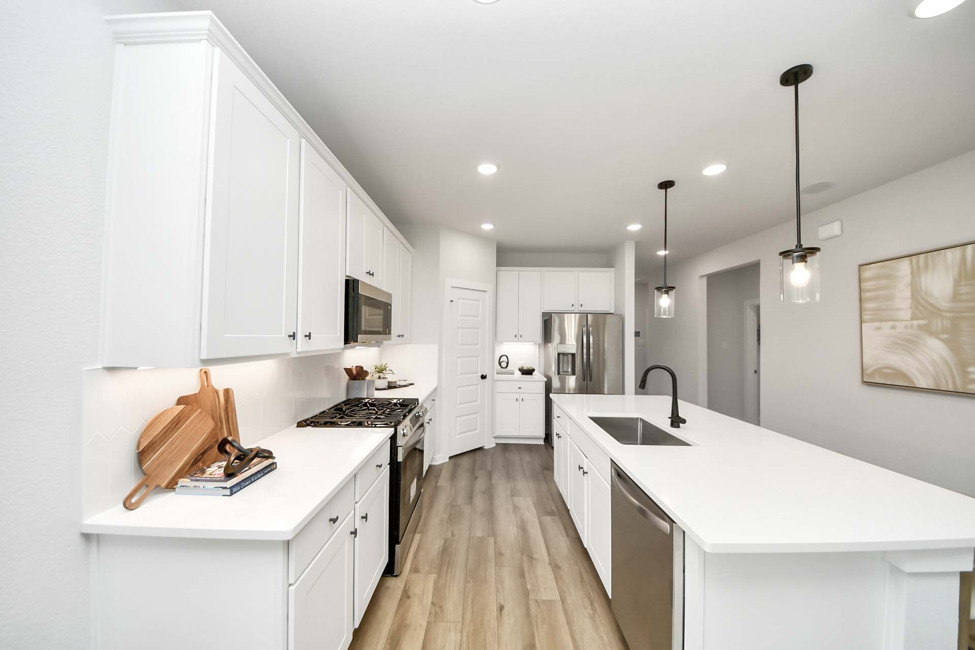 Modern kitchen at Enclave at Newport in Crosby, TX with white cabinets, quartz countertops, and stainless steel appliances.