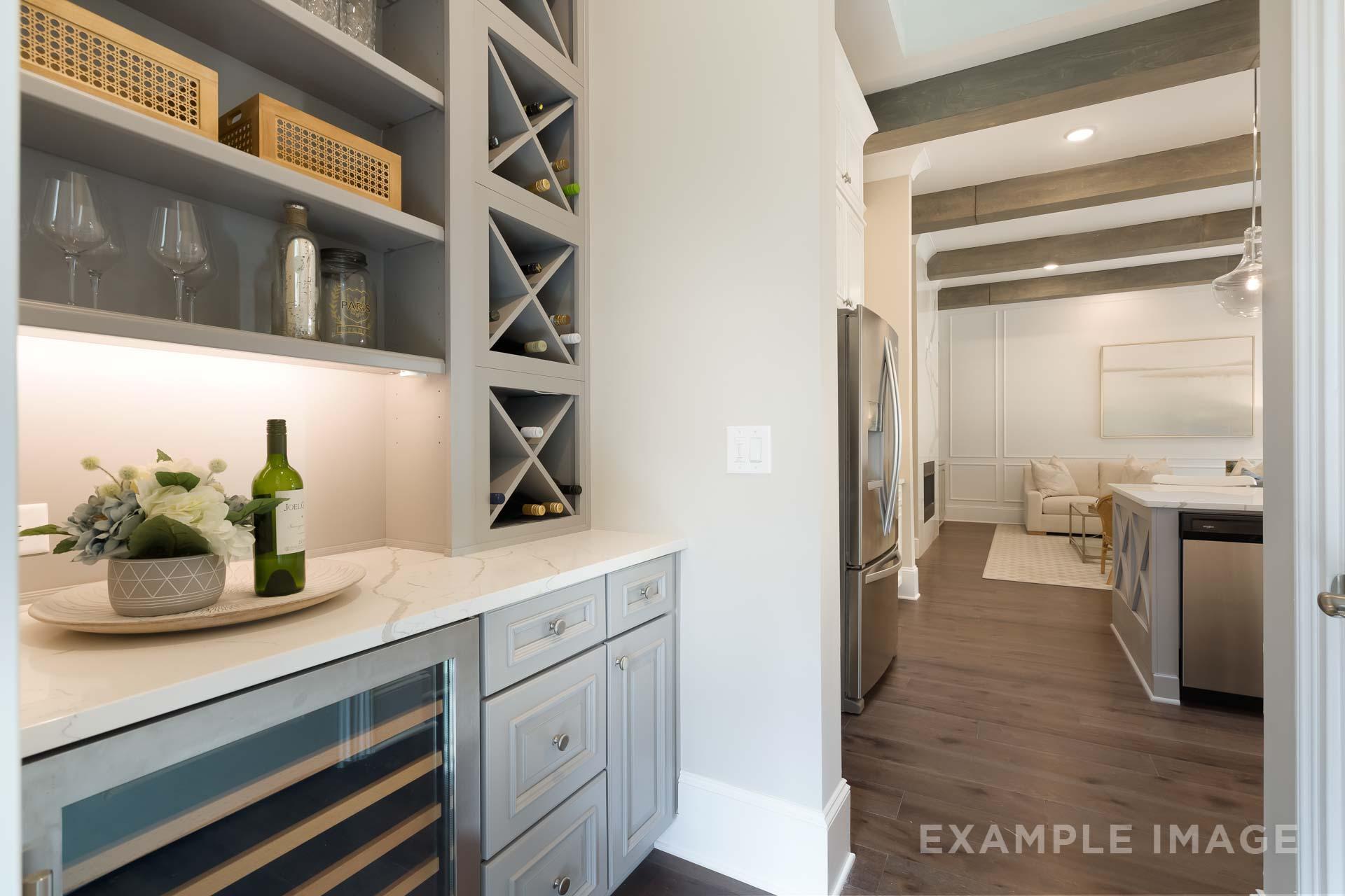 Butler's pantry in The Seaside C featuring wine racks, glassware, under-cabinet lighting, and open view to gourmet kitchen