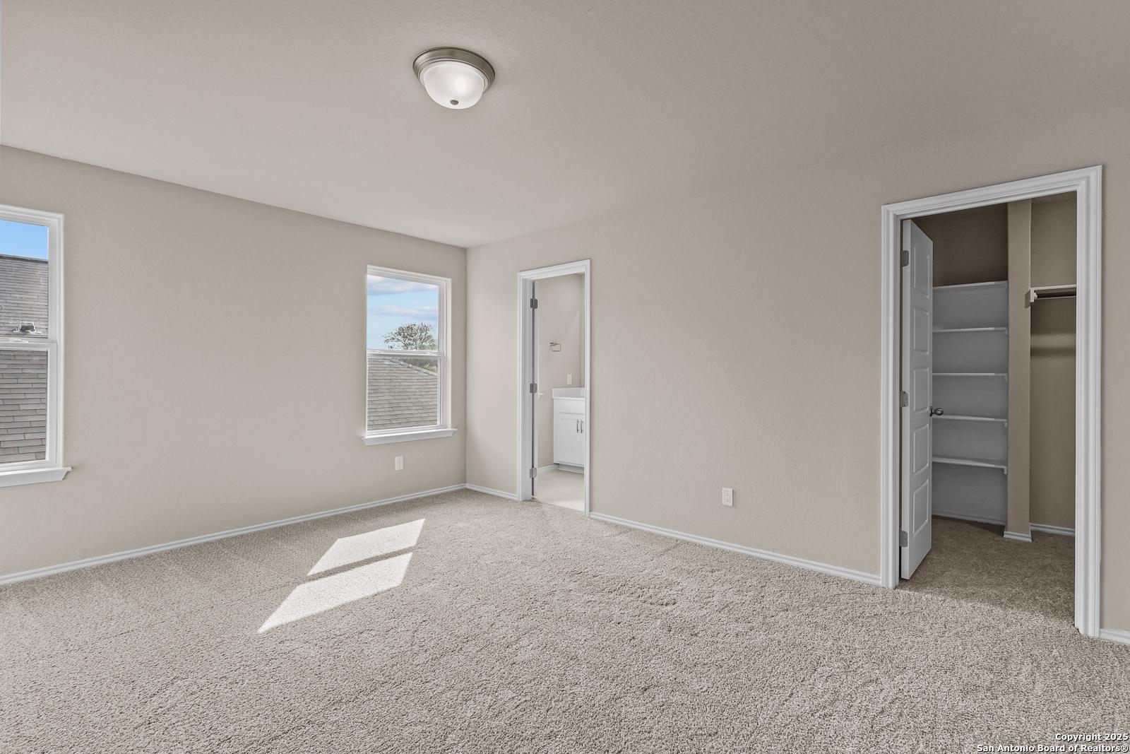 Light-filled bedroom with walk-in closet and en-suite bath in Davidson Homes The Douglas G, San Antonio, Texas